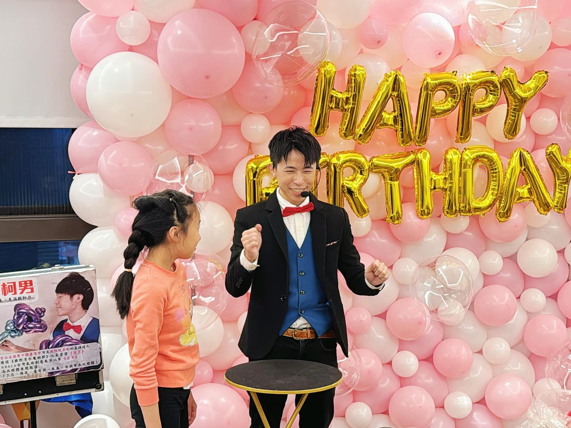 新北板橋生日派對，柯男與小壽星站在粉白氣球牆前表演