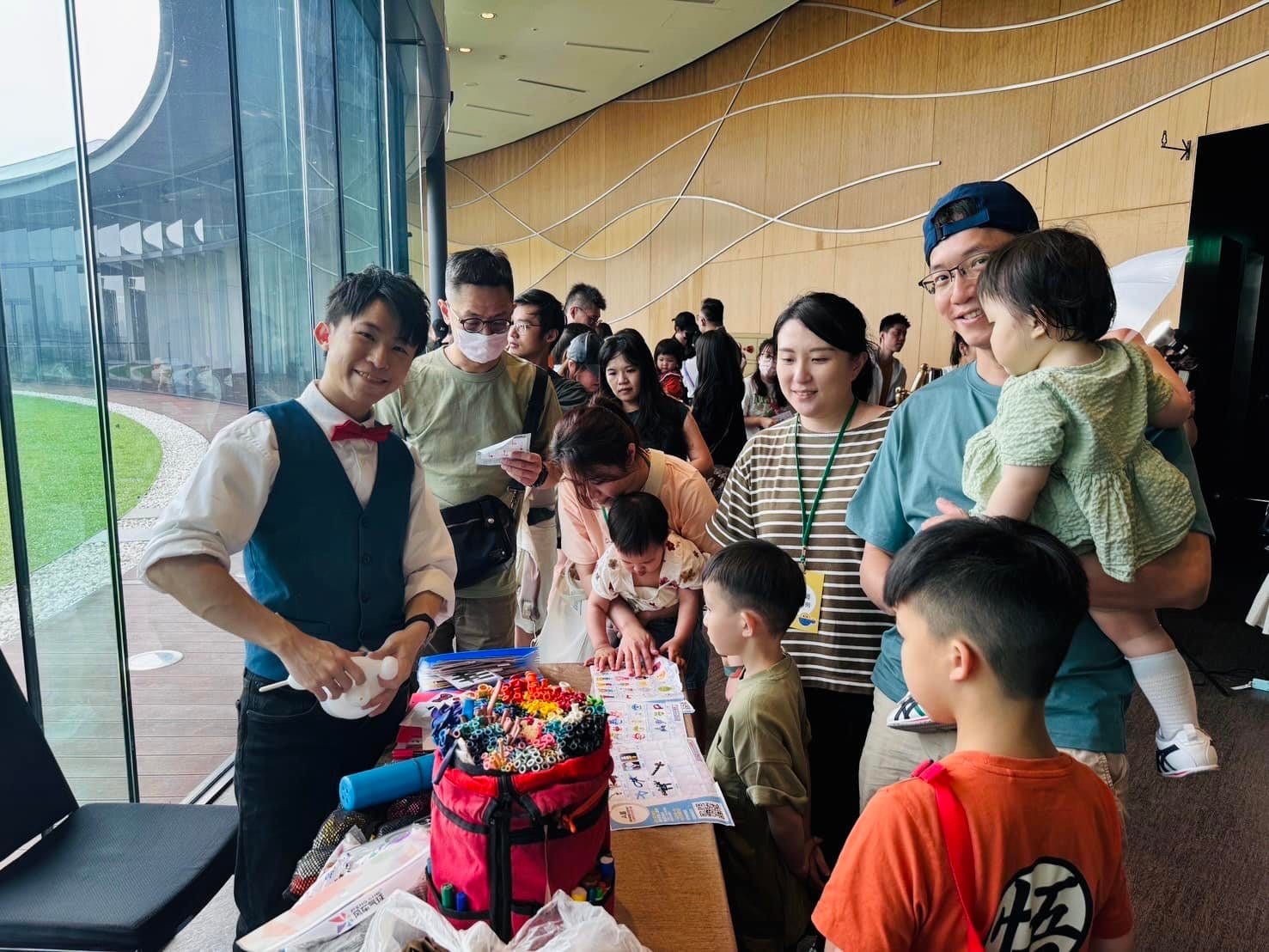 台北信義週年慶親子活動，家長抱著孩子在氣球攤位前排隊