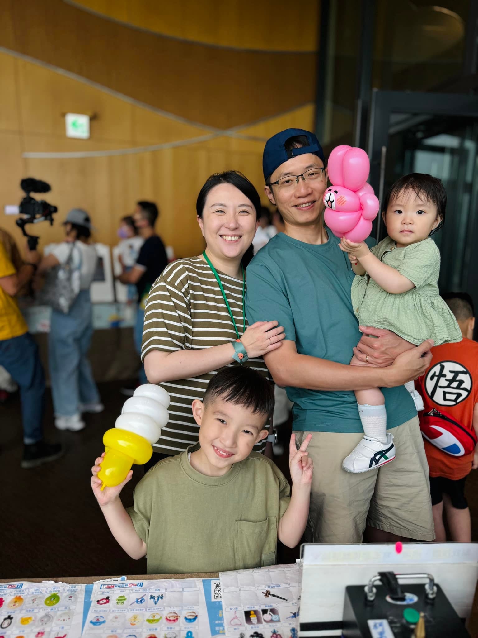 一家四口合照，孩子拿著冰淇淋與粉紅花朵造型氣球