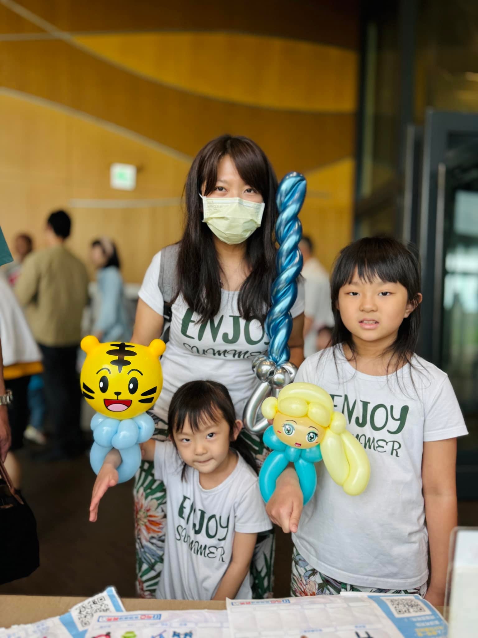 媽媽和孩子拿著巧虎手環、藍色寶劍與金髮公主氣球