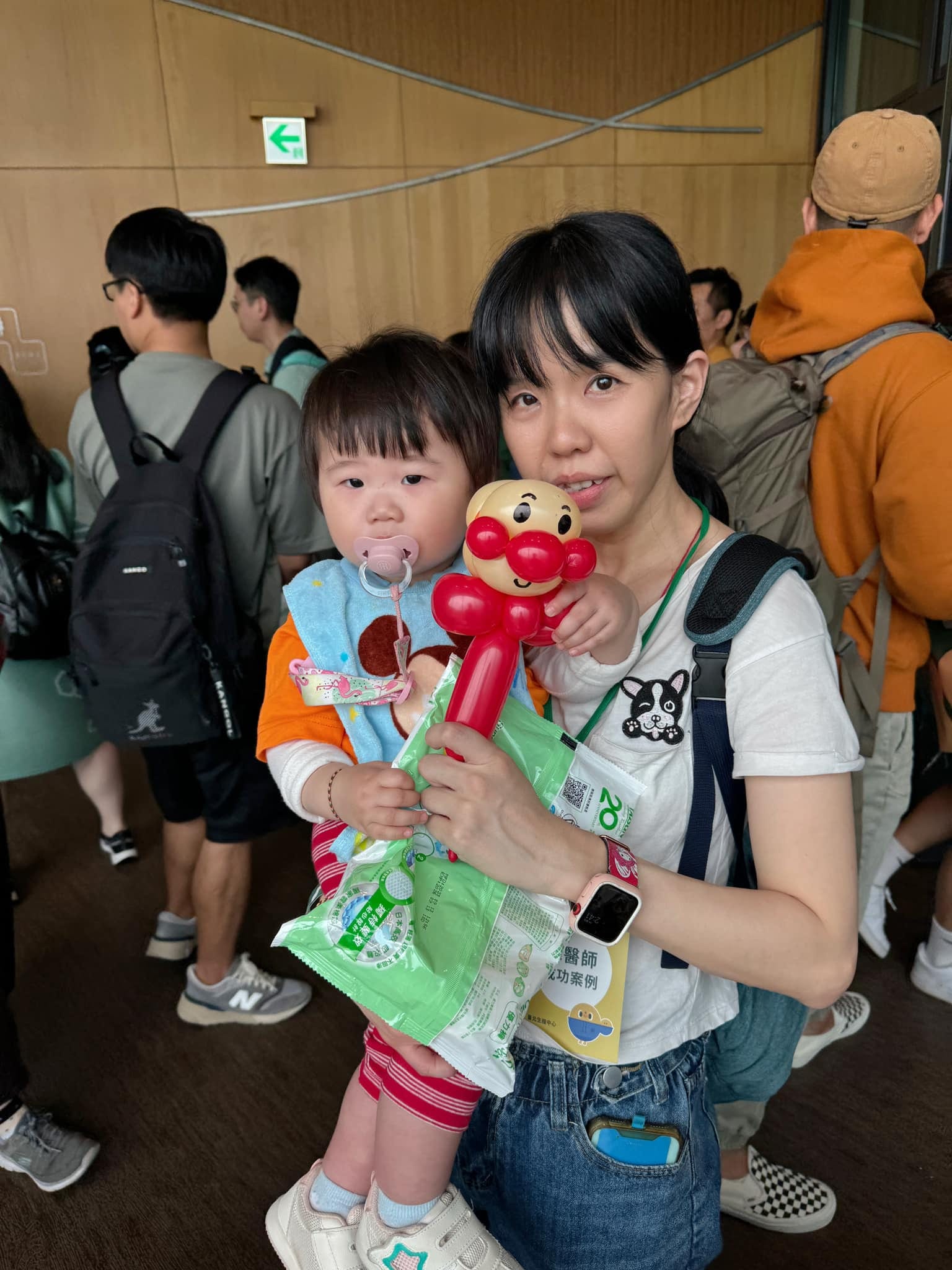 媽媽抱著小朋友，孩子手上拿著麵包超人造型氣球