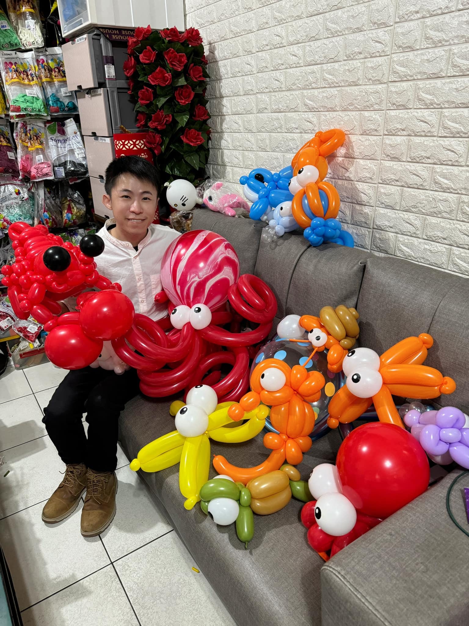 柯男坐在沙發上，身邊擺滿章魚、螃蟹、龍蝦等海洋生物氣球