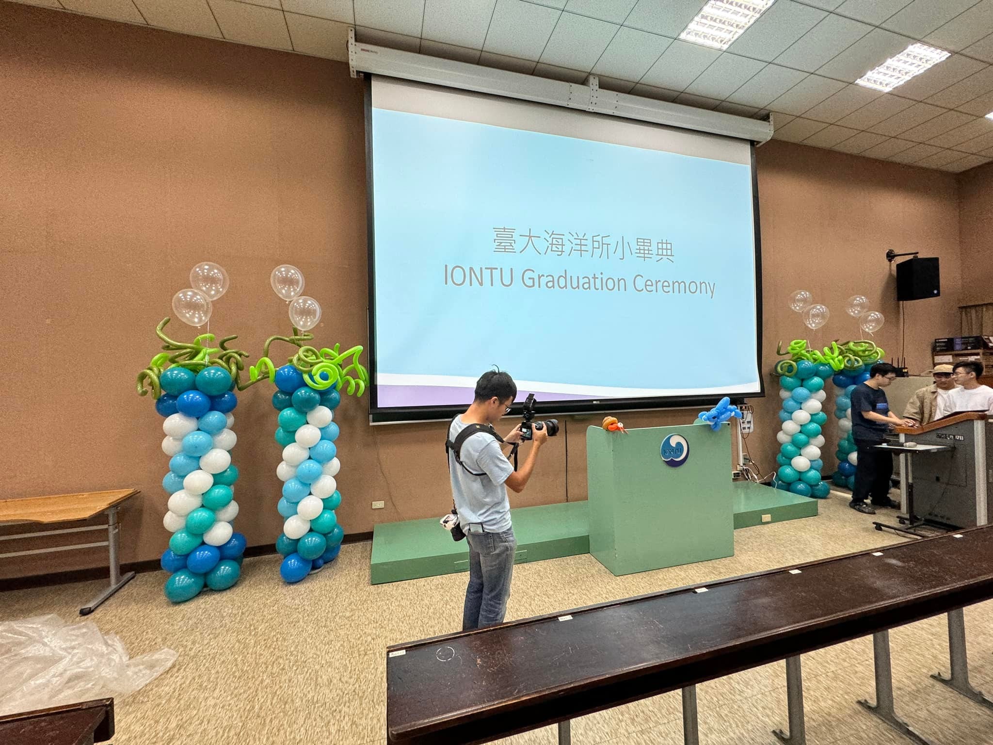 台大海洋所小畢典會場，投影幕兩側立著海草造型氣球柱