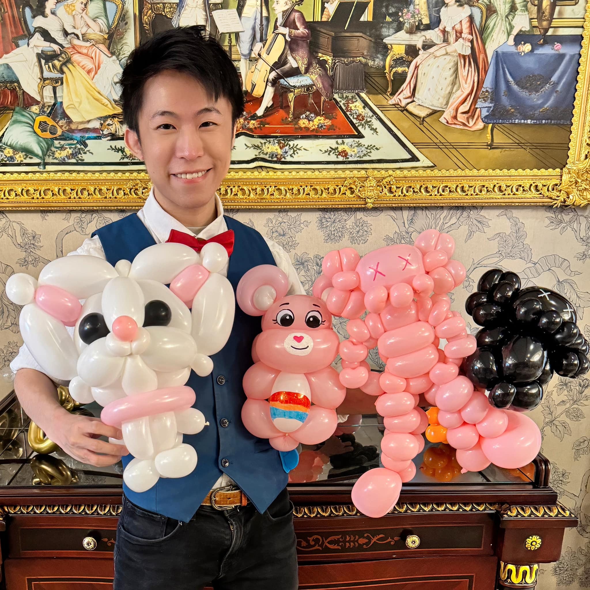 柯男在生日派對會場抱著白貓、彩虹熊、粉紅與黑色 Kaws 公仔造型氣球