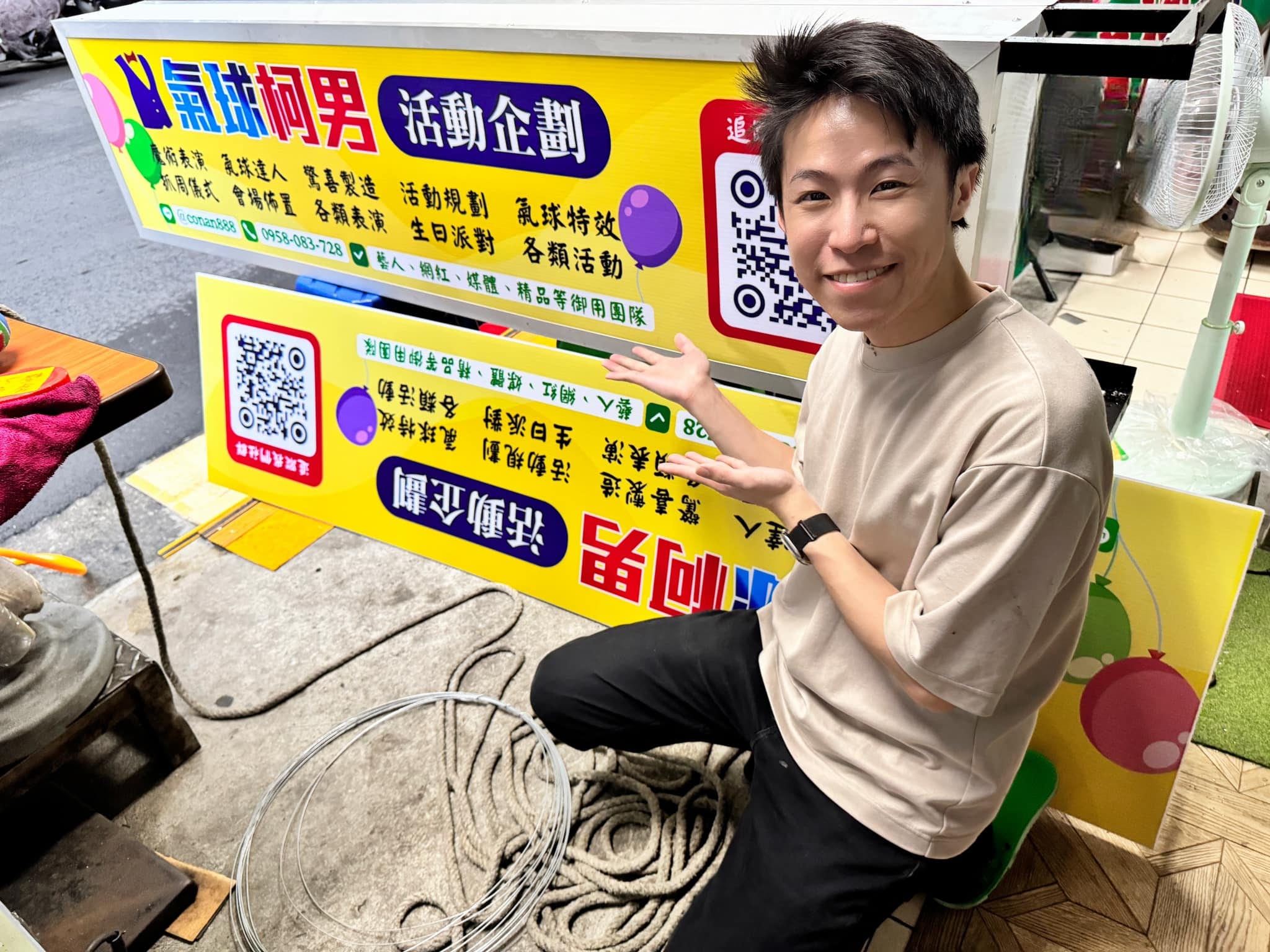 柯男蹲在剛做好的兩面黃色招牌旁開心比手勢