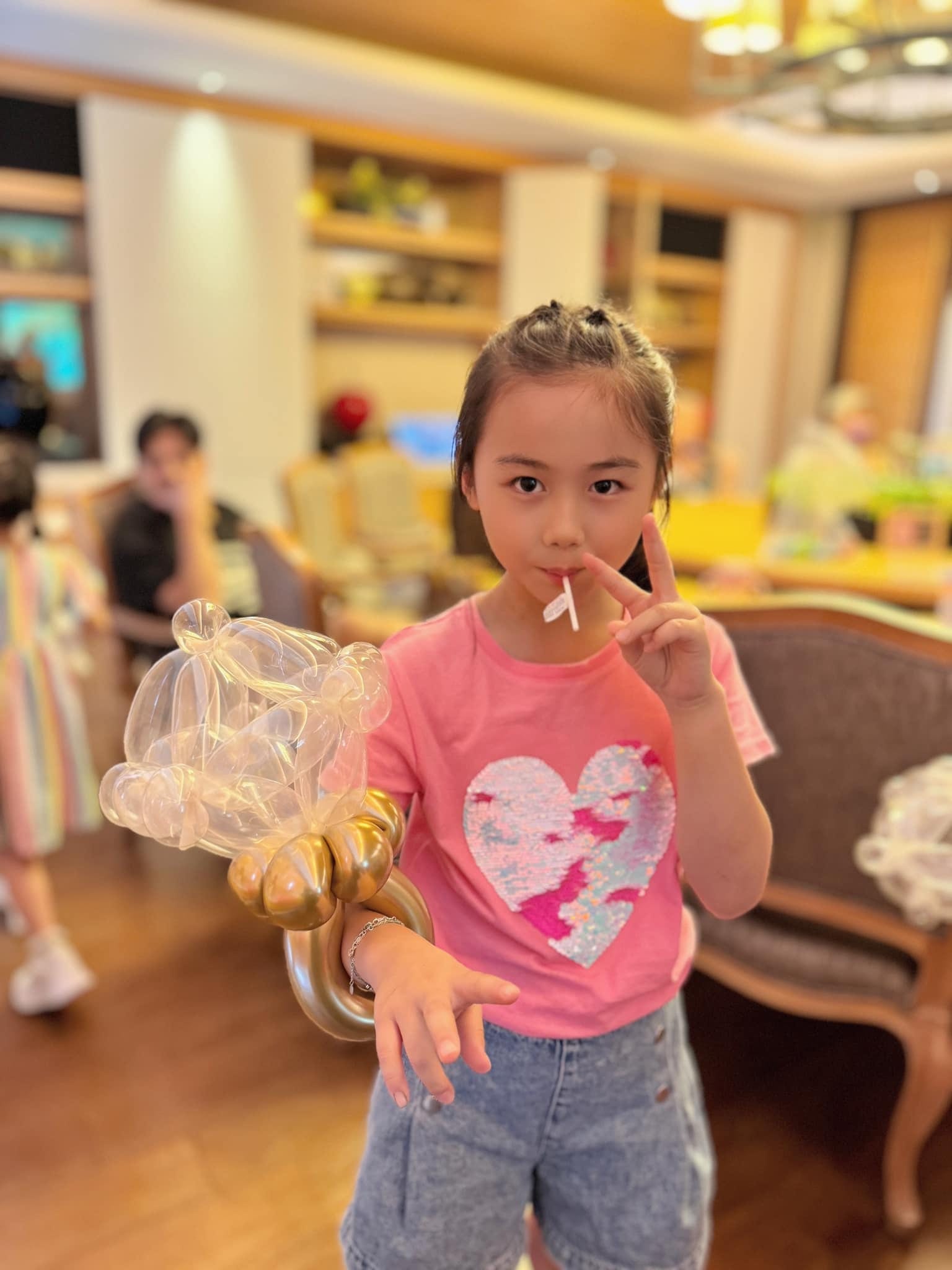 粉紅上衣女孩比手勢，手上戴著透明泡泡金色氣球