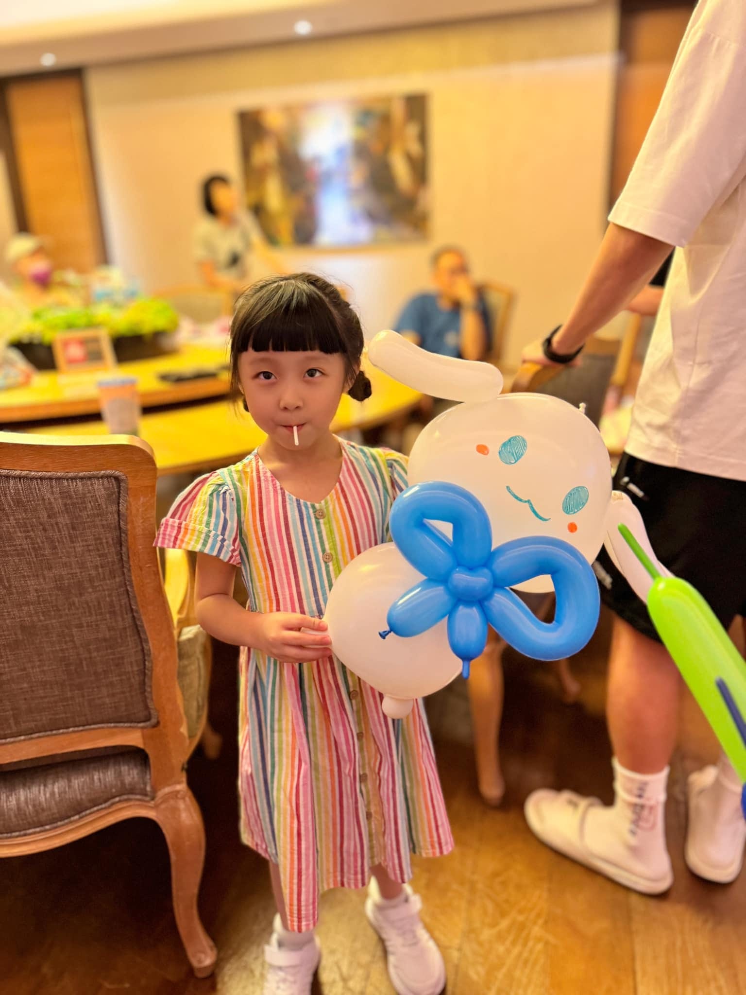 穿彩色條紋洋裝的女孩抱著大耳狗造型氣球