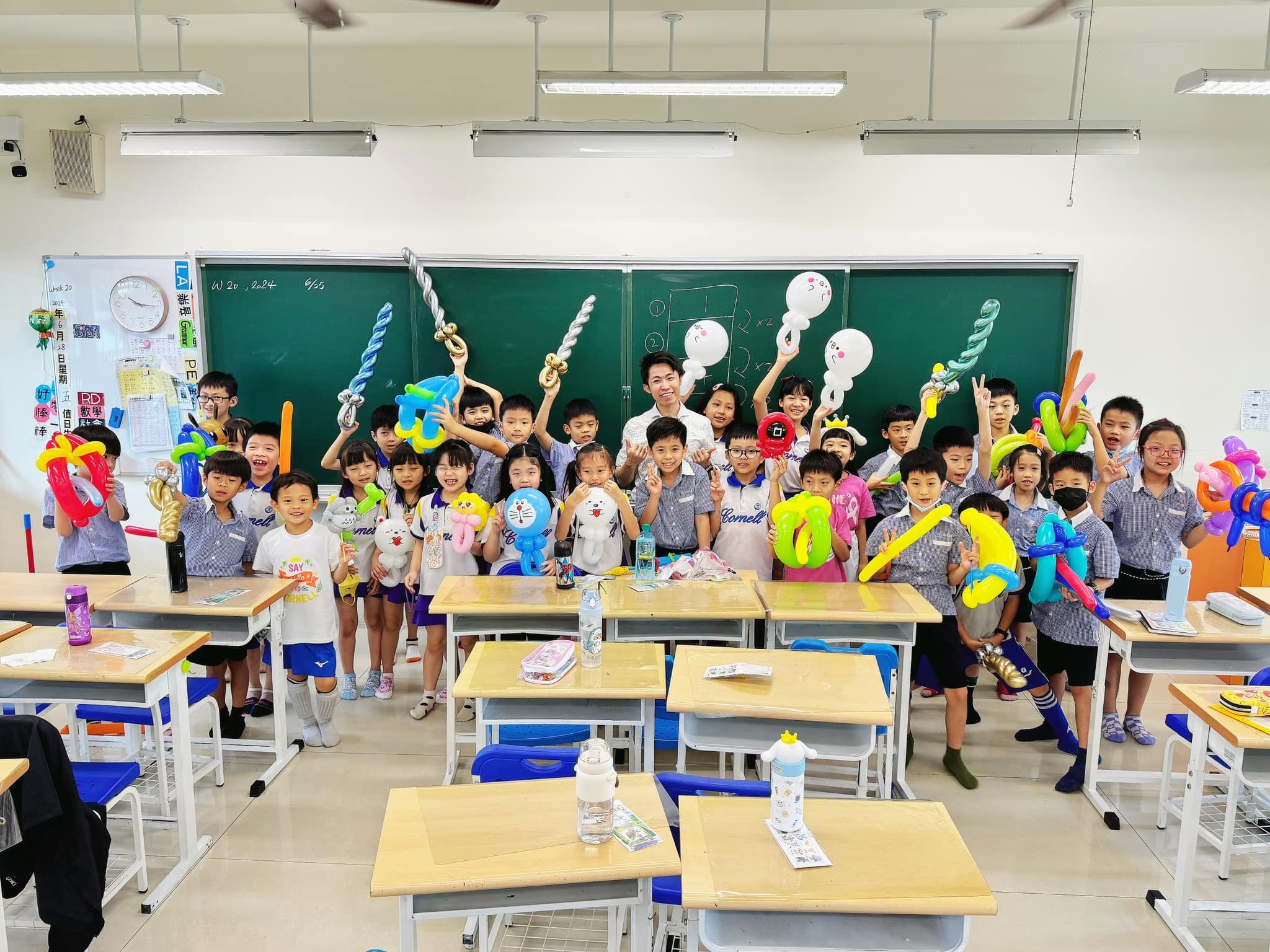國小教室裡，魔術社學生舉著寶劍、花朵等造型氣球和柯男合照