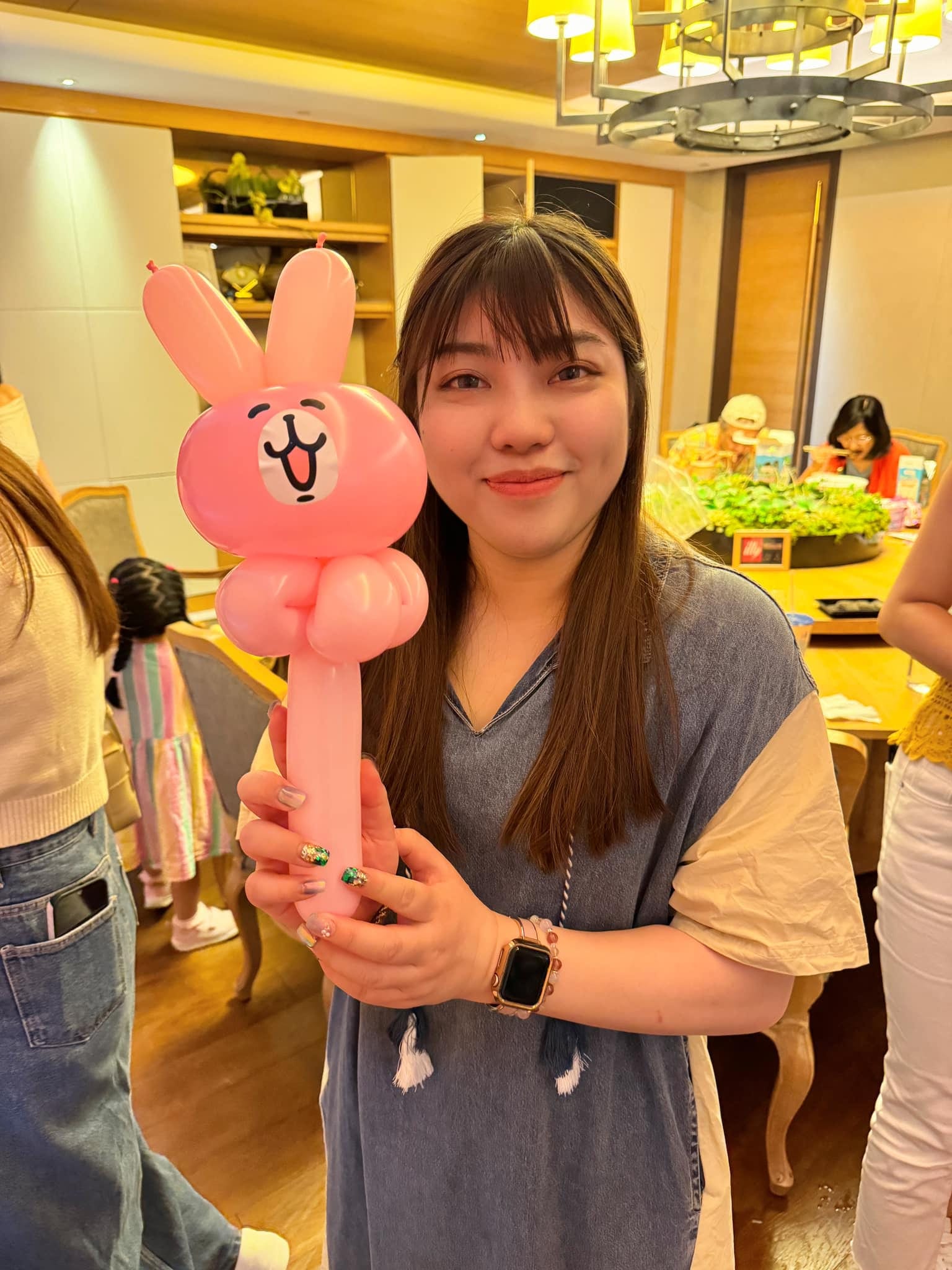 女士拿著粉紅色兔子臉造型氣球棒露出笑容