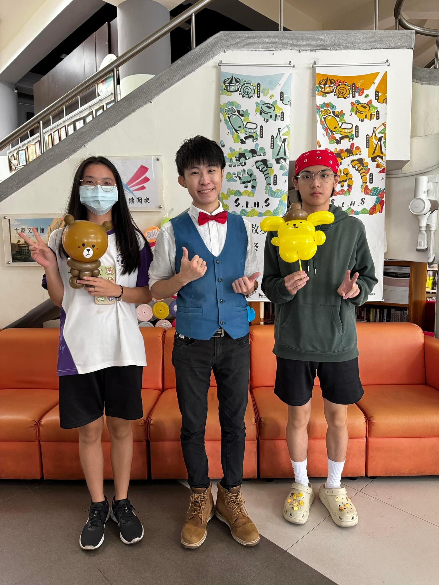兩位學生分別拿著熊大與布丁狗造型氣球和柯男合照