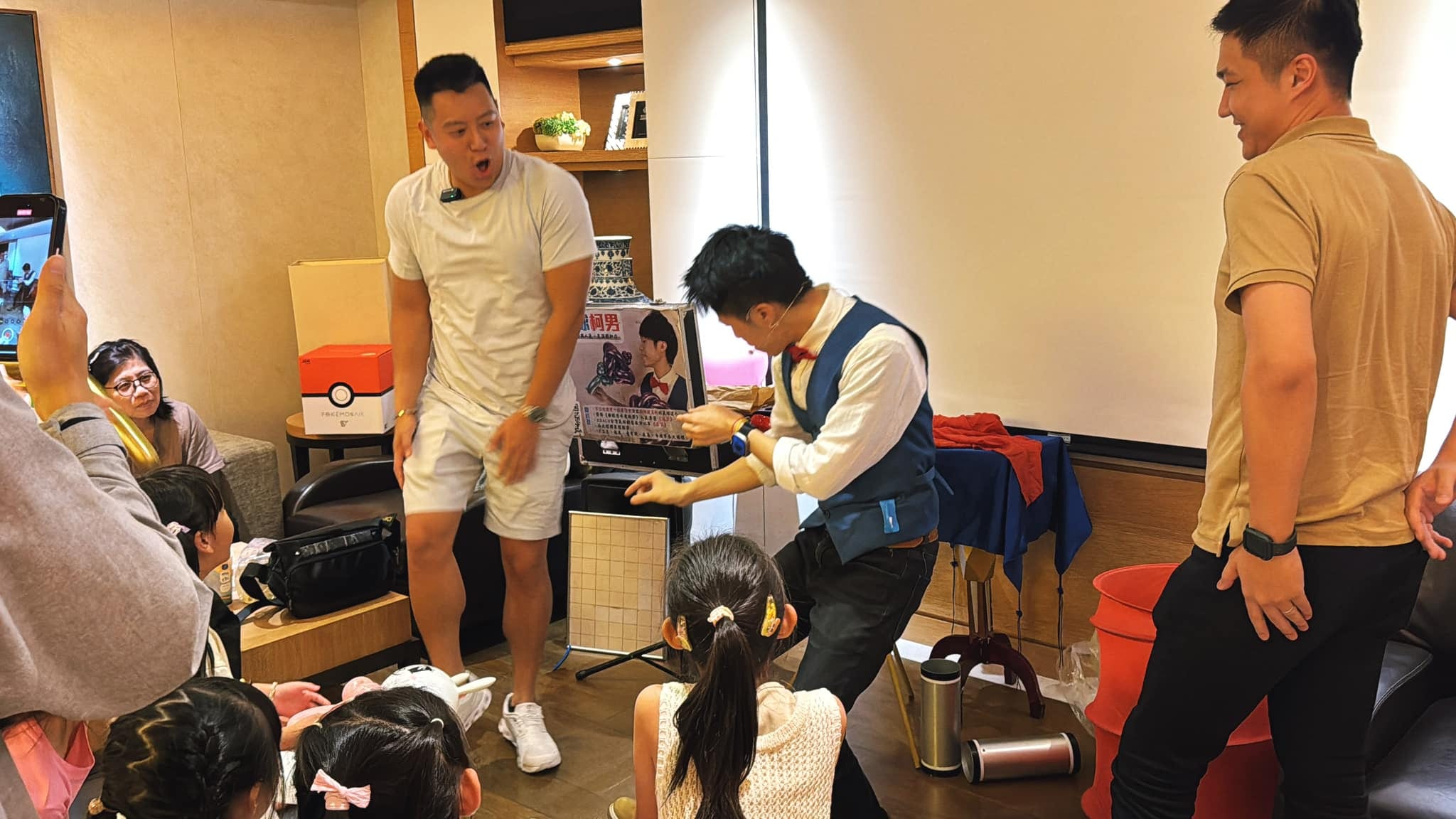 兩位男士上台協助魔術，孩子們坐在地上圍觀