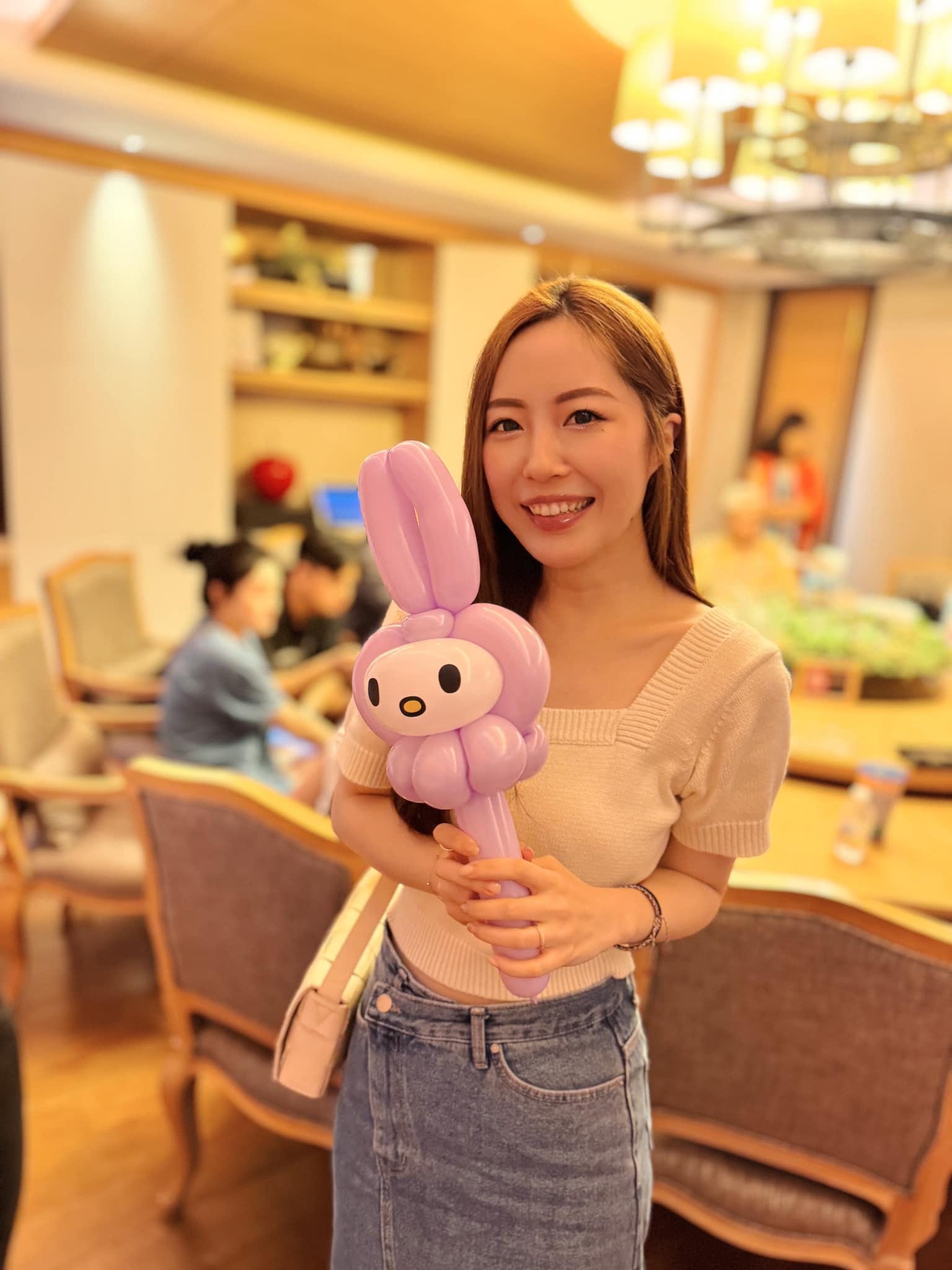 女士微笑拿著淡紫色美樂蒂造型氣球棒
