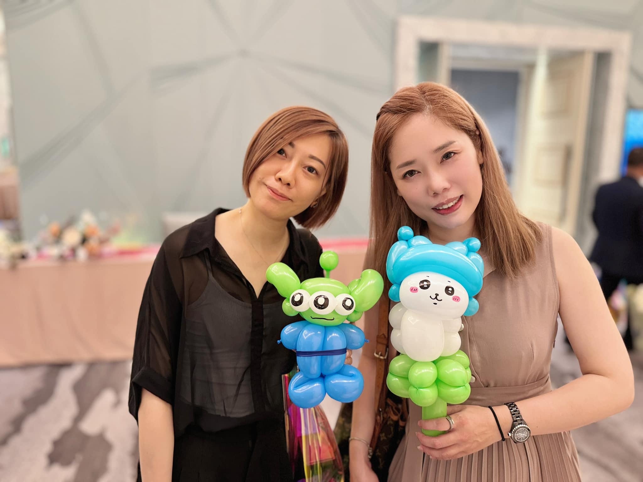 兩位女賓客拿著綠色三眼怪與藍帽白色角色造型氣球合照