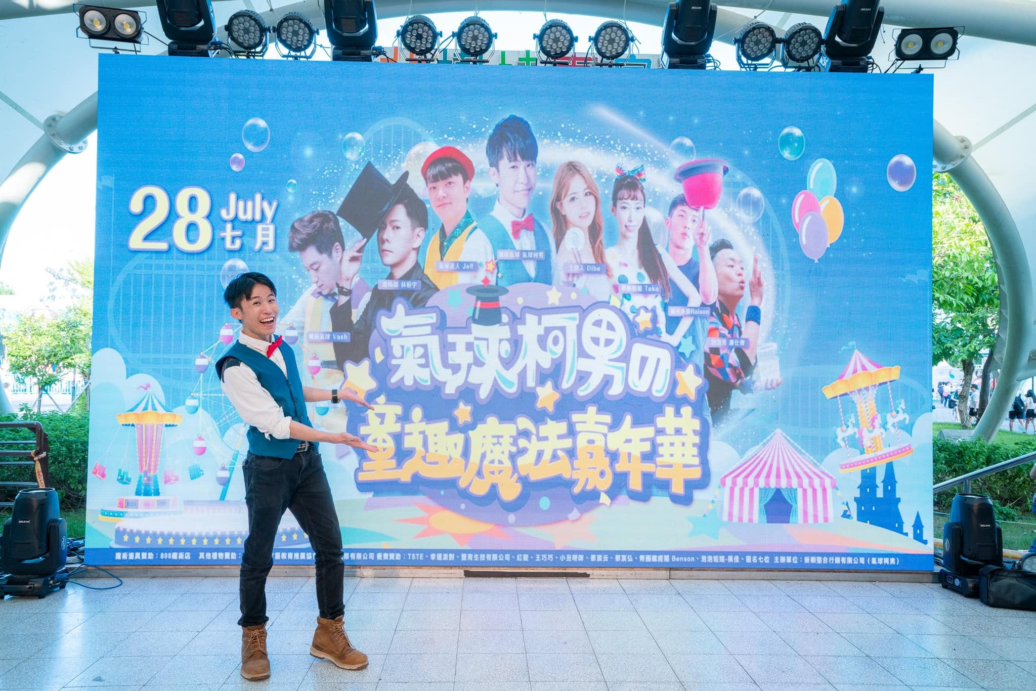 柯男站在印著「氣球柯男の童趣魔法嘉年華」的大型螢幕前開場