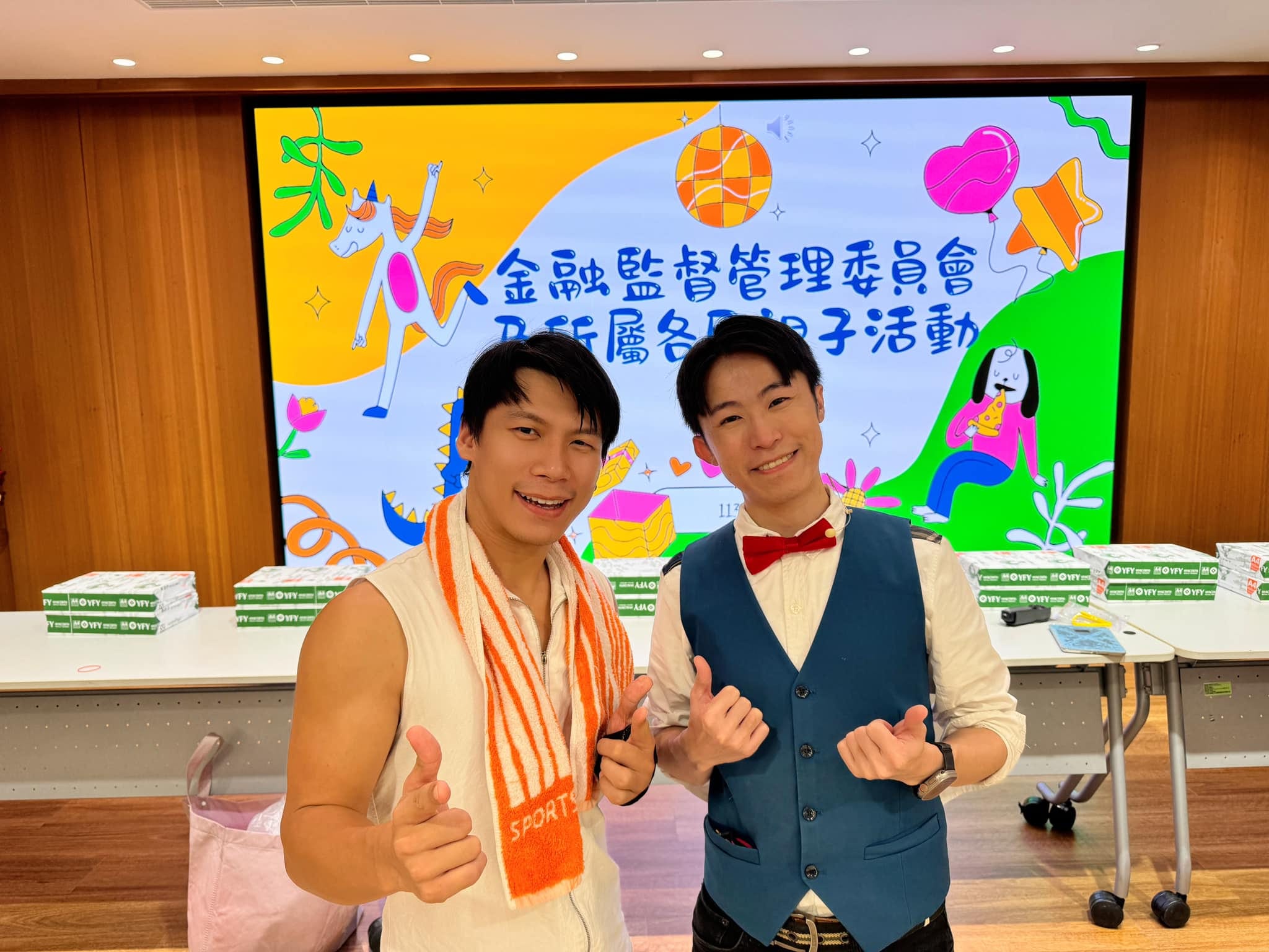 柯男和另一位表演者在親子活動主視覺螢幕前比讚合照