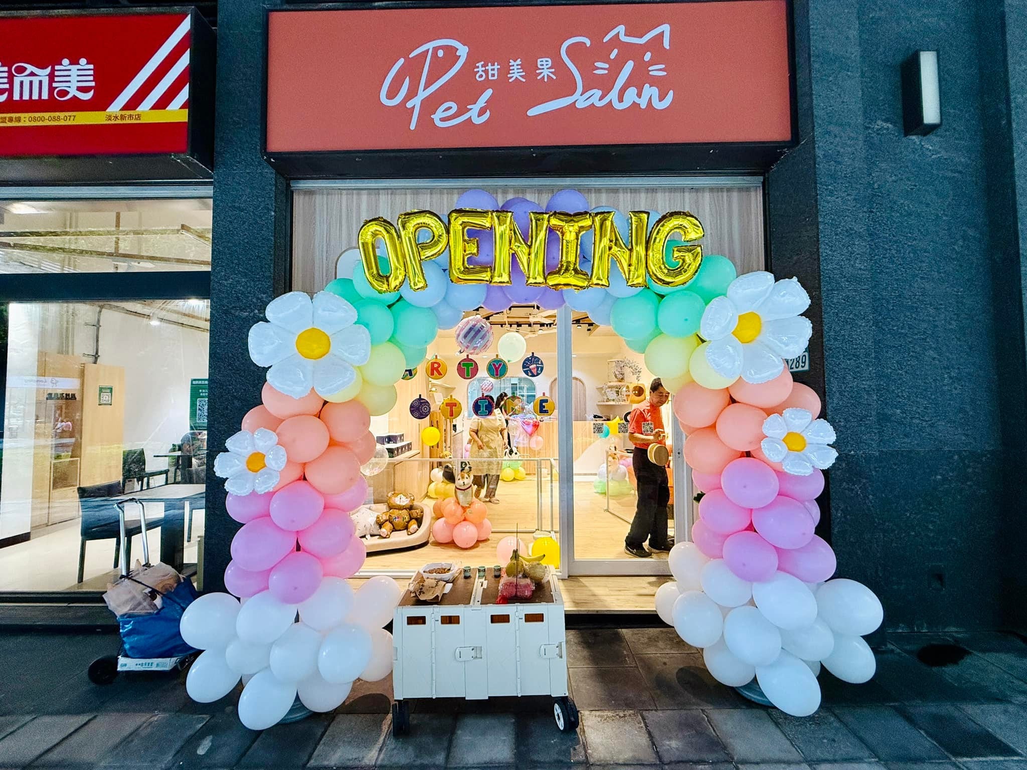 新北淡水寵物美容店門口的馬卡龍色開幕氣球拱門，頂端掛著金色 OPENING 字母氣球