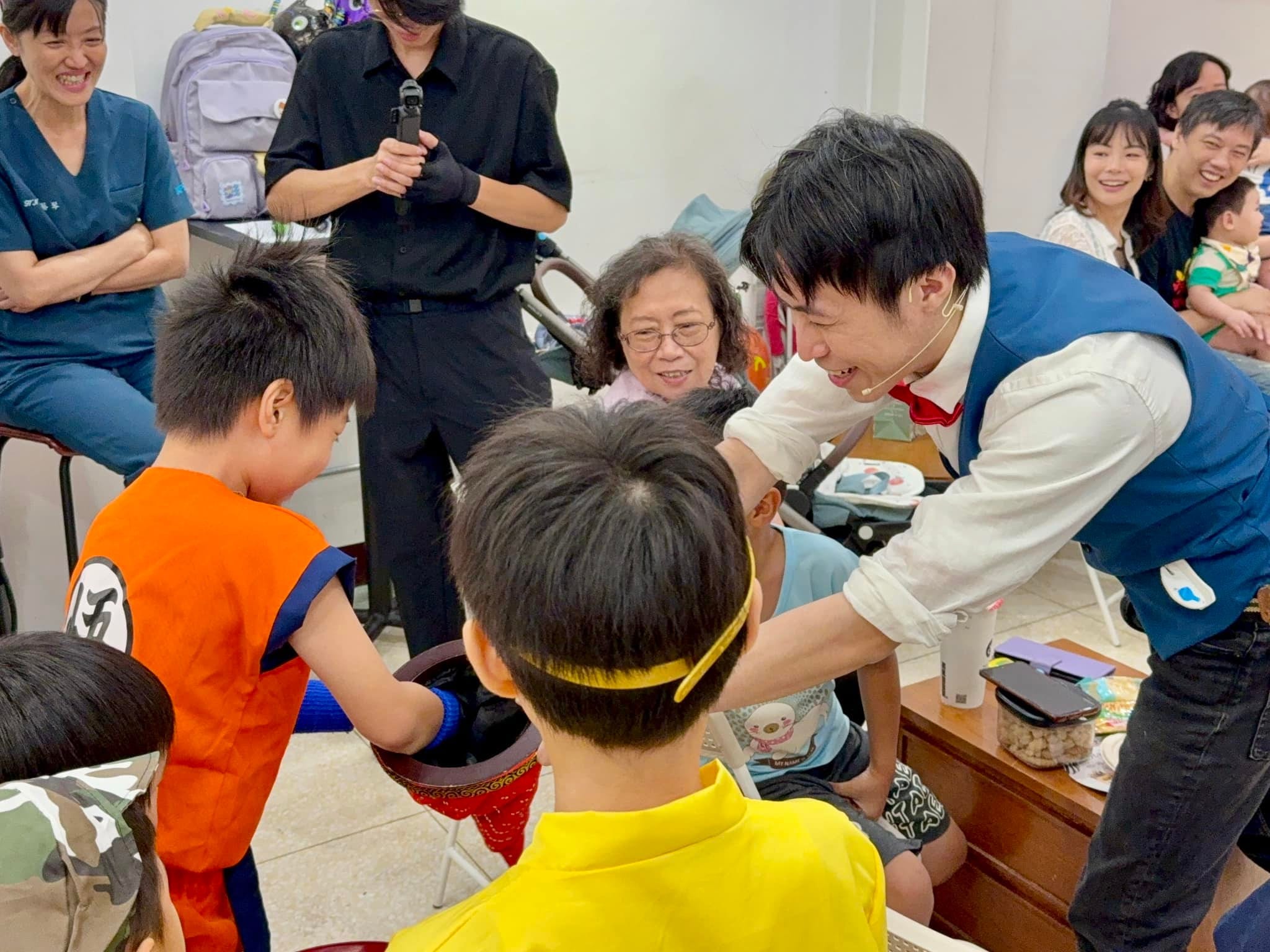 柯男彎腰請穿萬聖節服裝的小朋友伸手參與魔術，旁邊家長笑著觀看