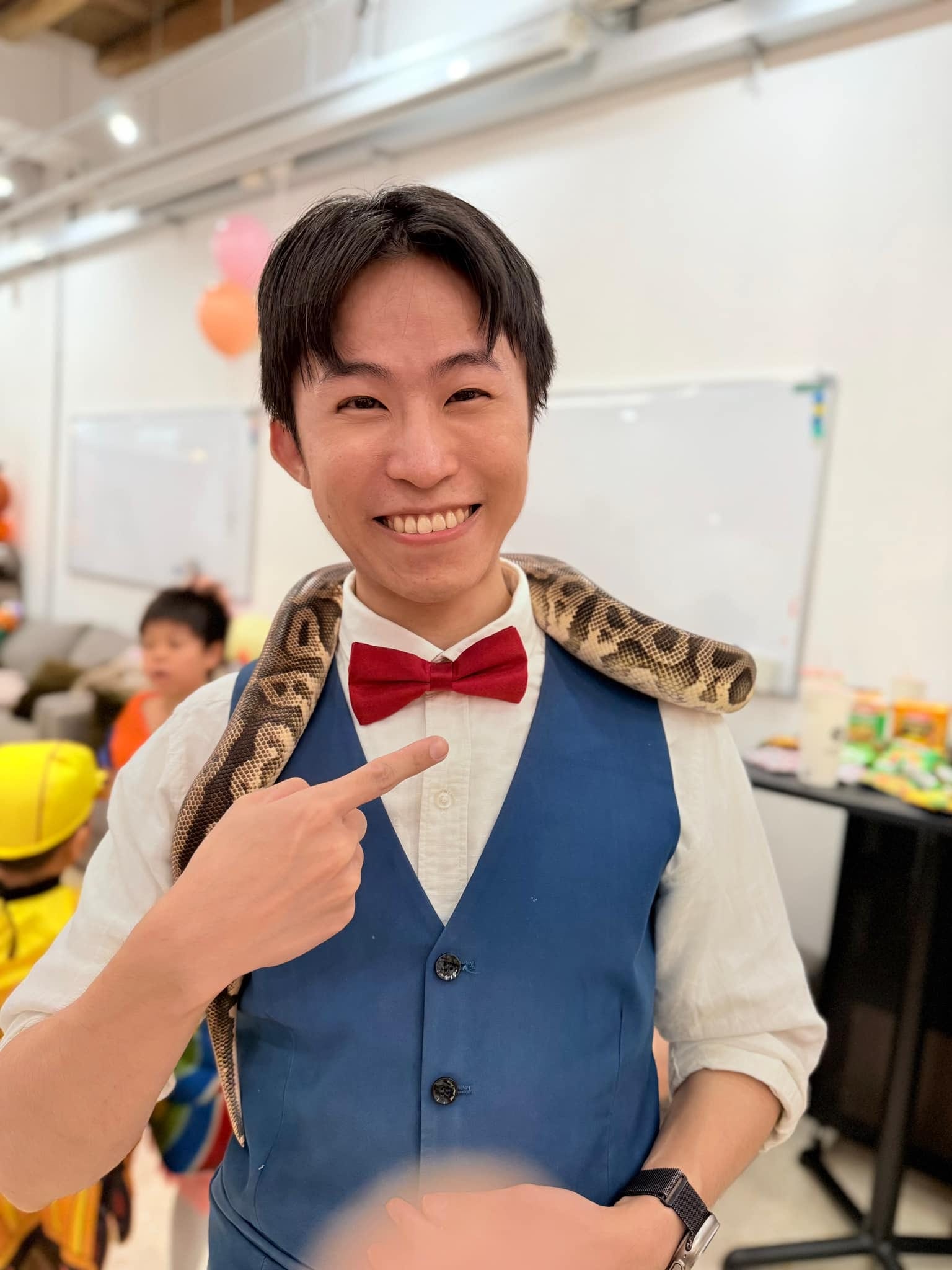 柯男肩上掛著生態老師帶來的蛇，笑著用手指向牠