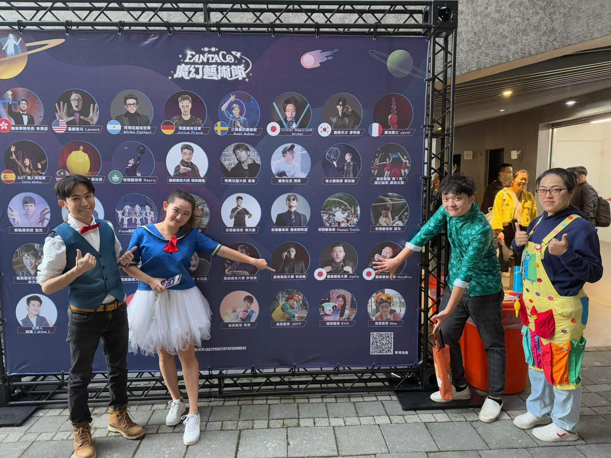 柯男與夥伴在 FANTACO 魔幻藝術節國內外表演者看板前擺姿勢
