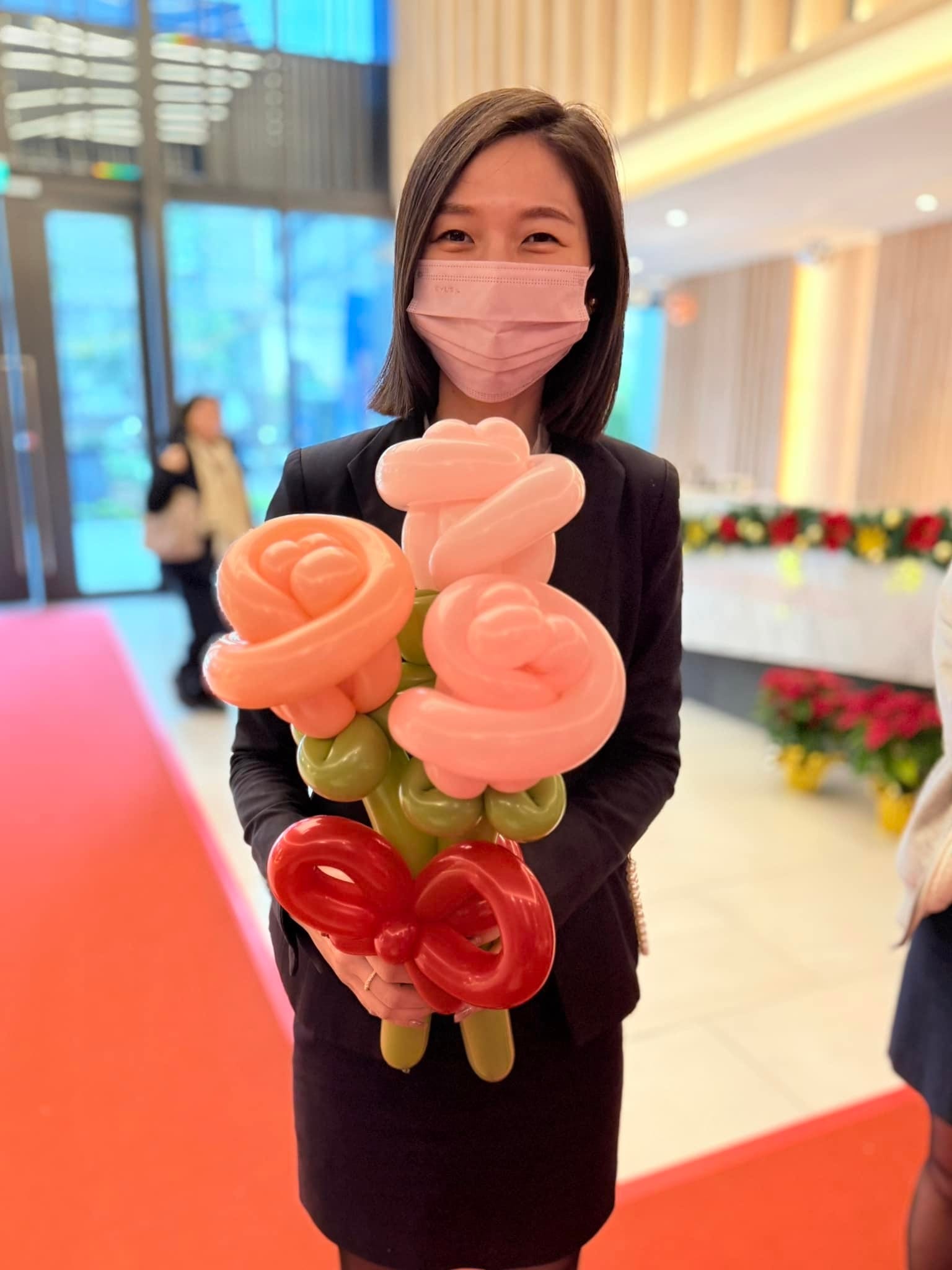 後續週六：穿黑西裝的女士捧著粉橘玫瑰造型氣球花束