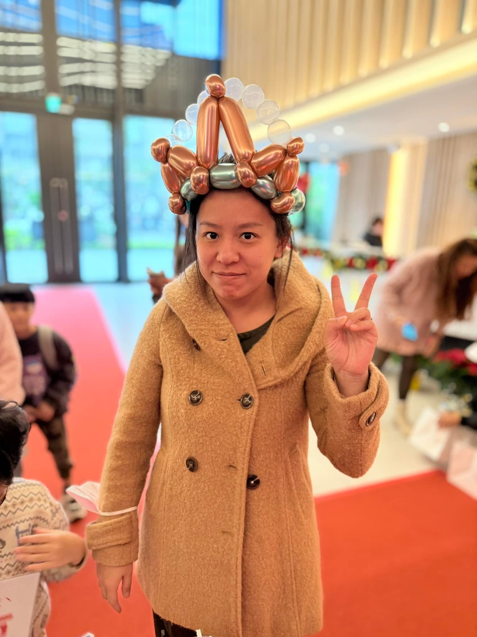 後續週六：穿駝色大衣的女士頭戴玫瑰金氣球皇冠比 YA