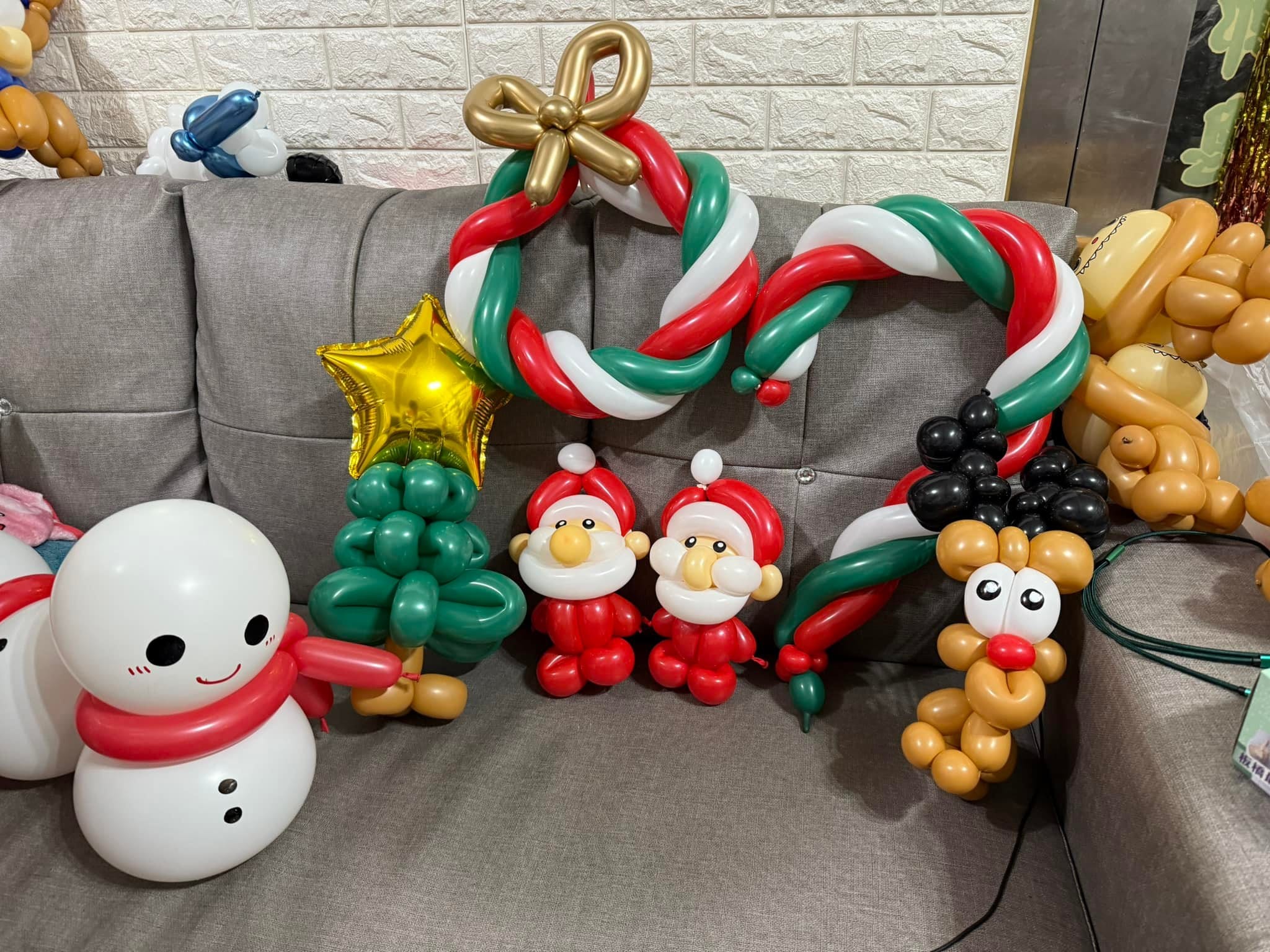 雪人、綠色聖誕樹、兩位聖誕老公公、黑耳麋鹿與拐杖糖造型氣球排在沙發上