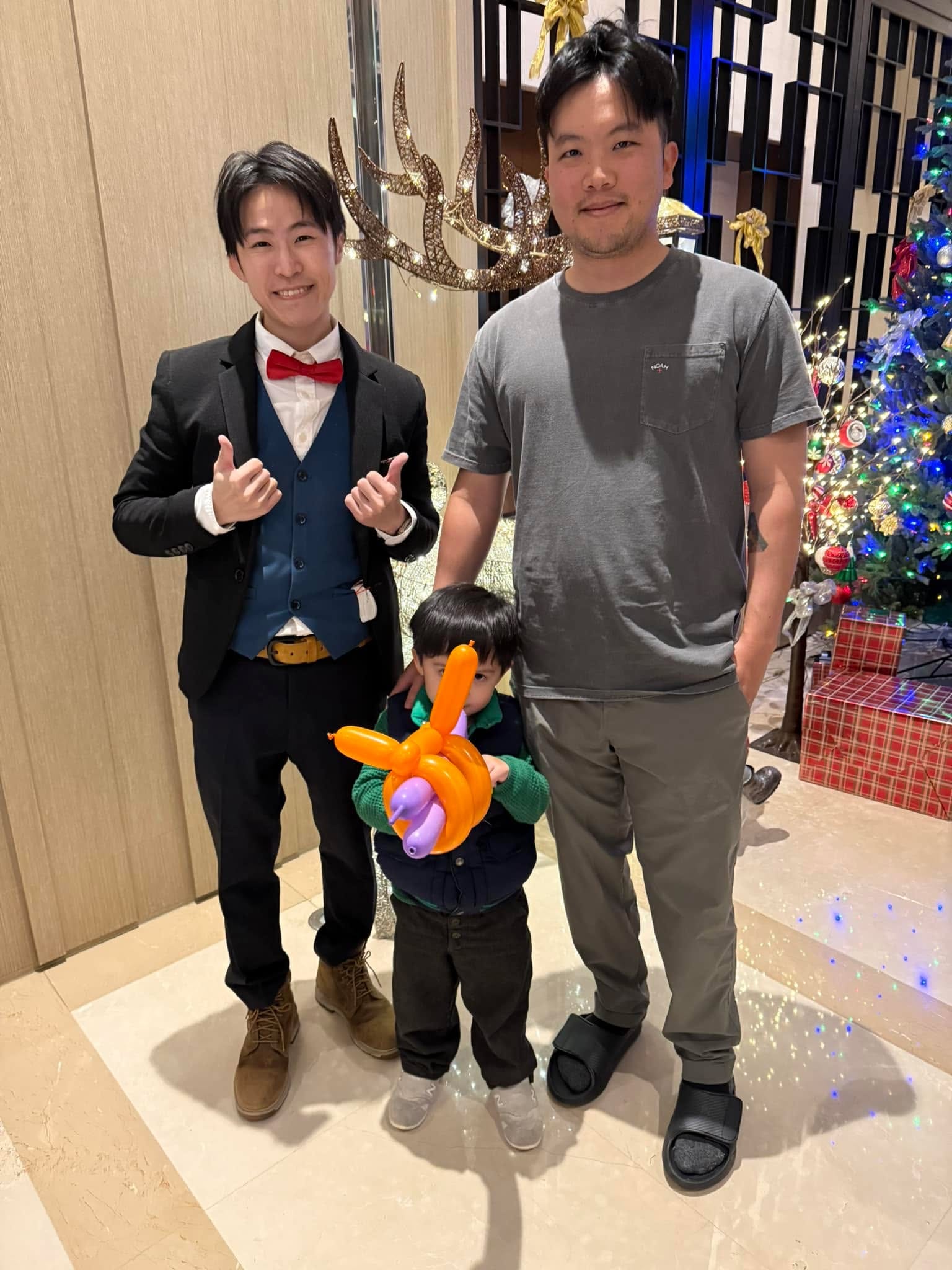 社區魔術演出後，穿背心打紅領結的我和謝孟恭合照，小朋友拿著橘色造型氣球