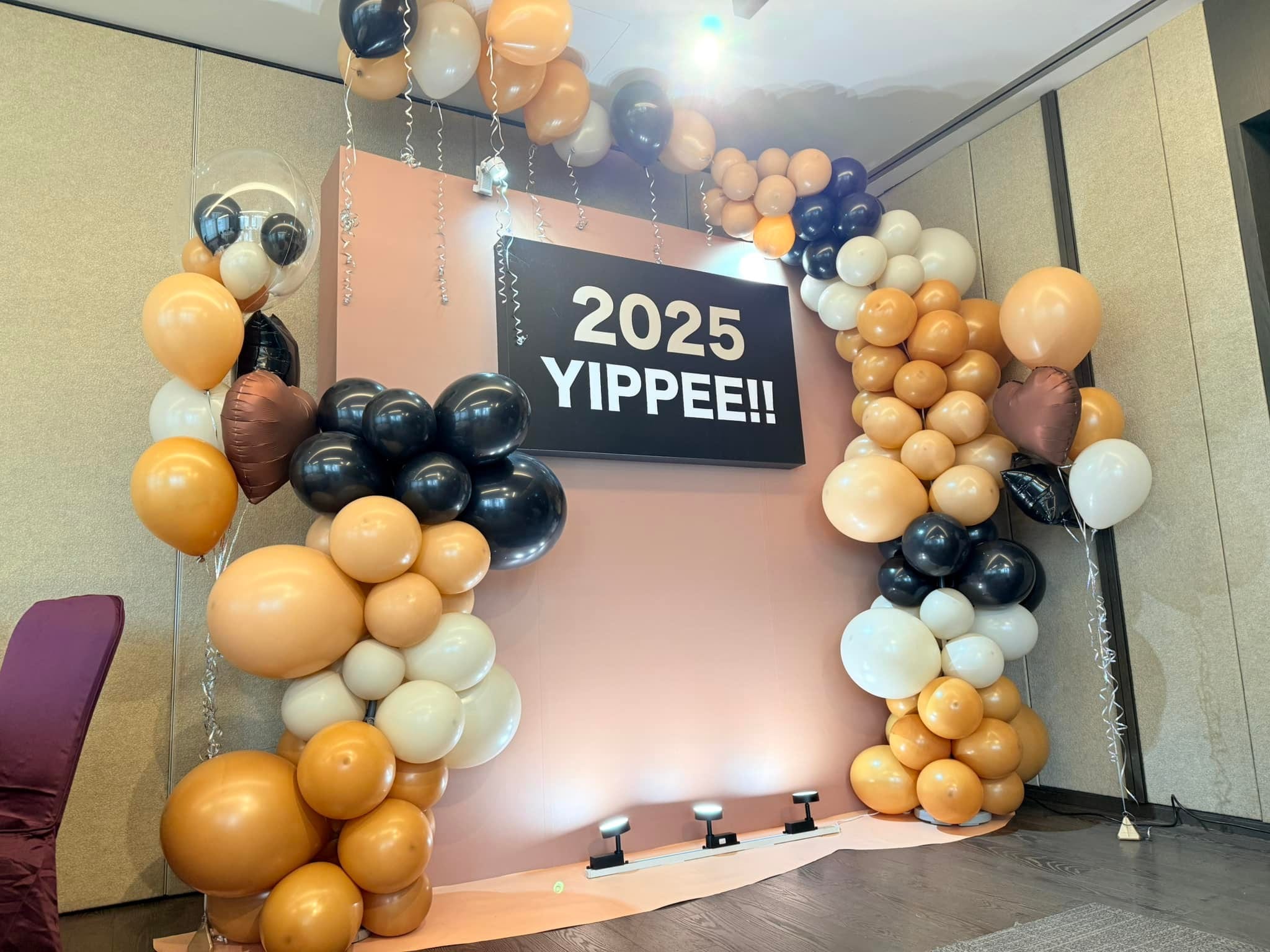 2 月春酒場：奶茶色、黑色與白色氣球拱，中間是 2025 YIPPEE 看板