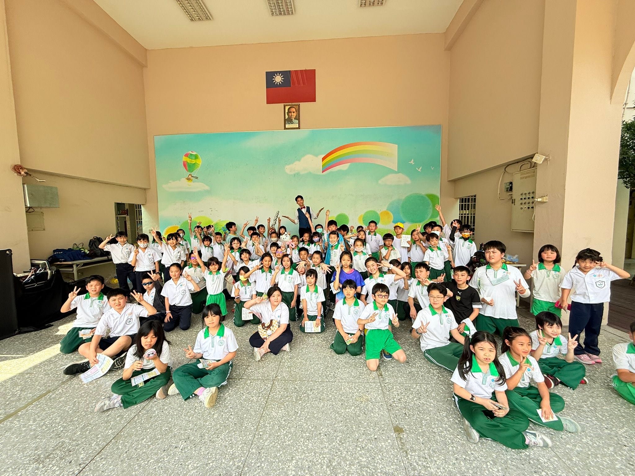 彩虹壁畫前，柯男張開雙手和一大群比 YA 的小學生合照