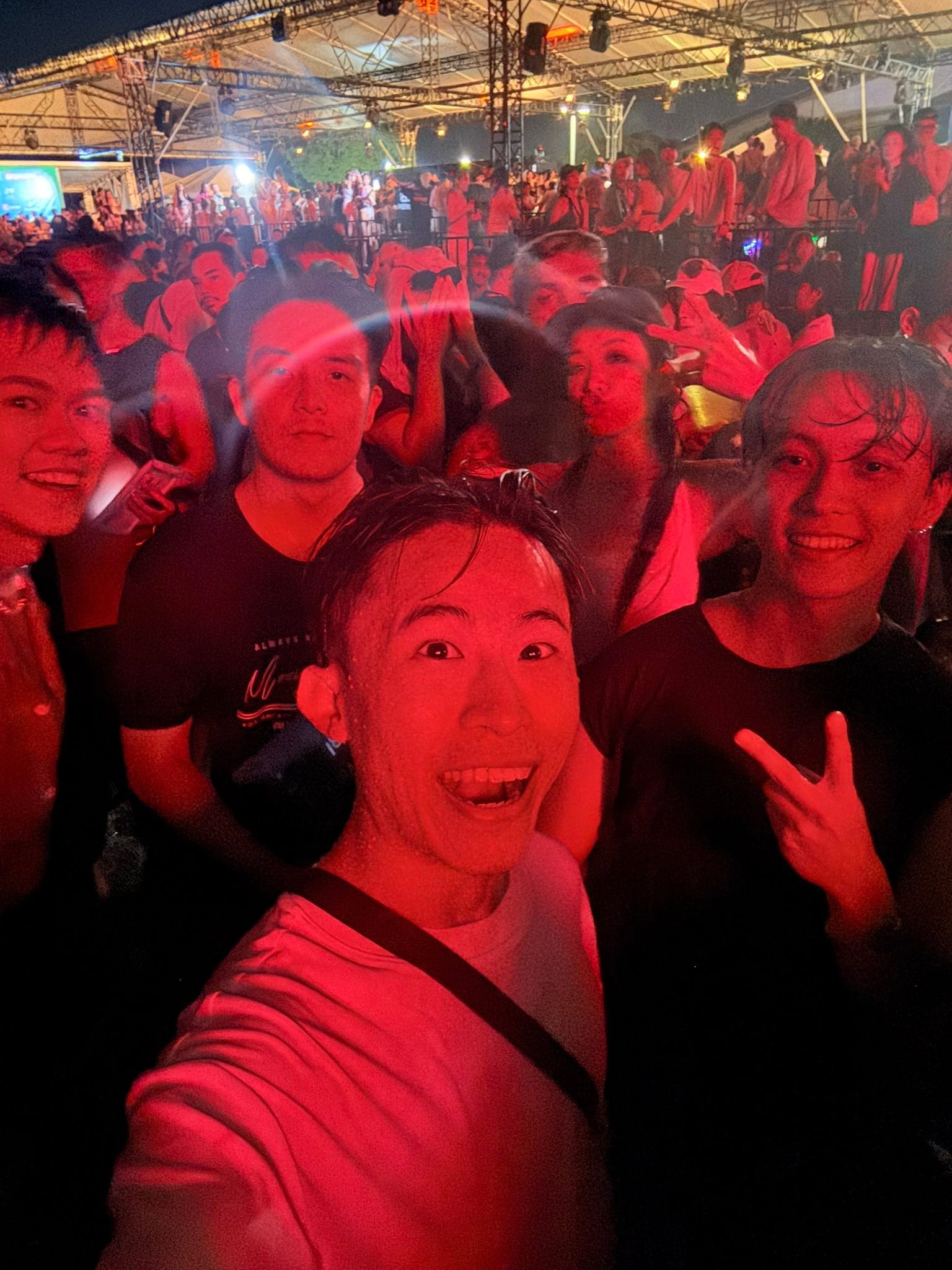 夜晚紅色燈光下，我和朋友在人群中自拍
