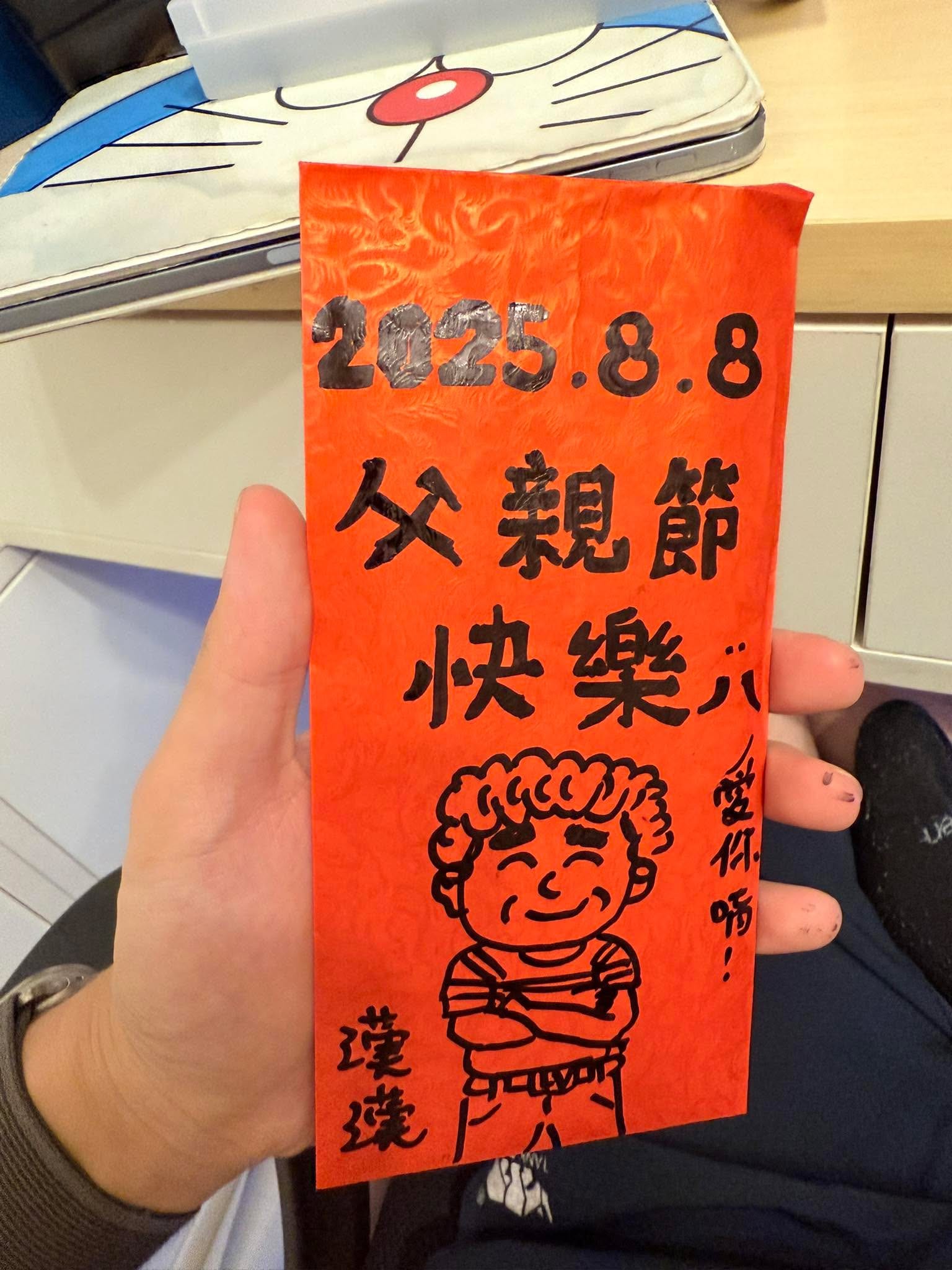 手上拿著寫著 2025.8.8 父親節快樂的手繪紅包