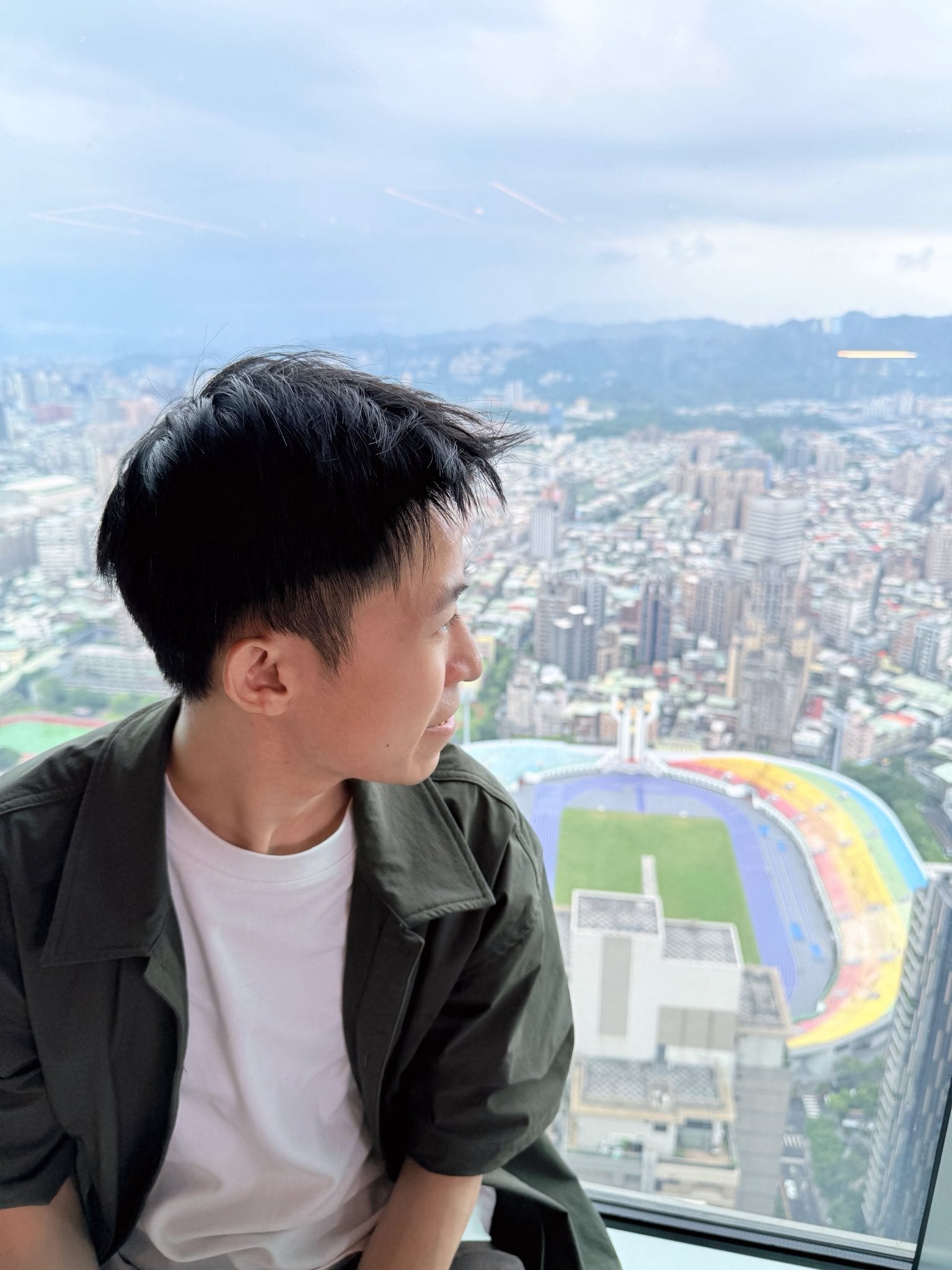 我坐在高樓窗邊，窗外是城市景色和田徑場