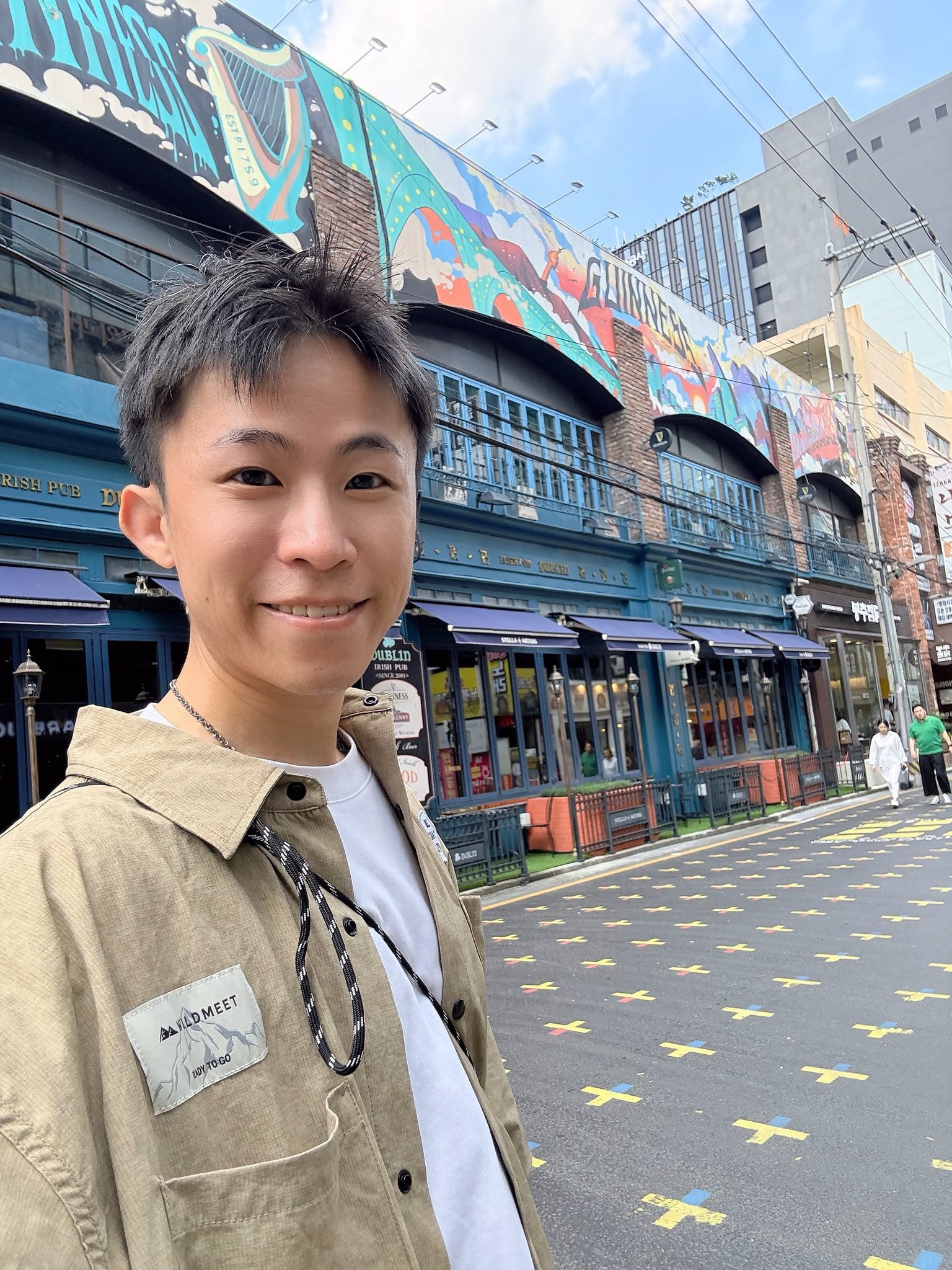 我在首爾街頭自拍，背後是彩繪牆面的建築