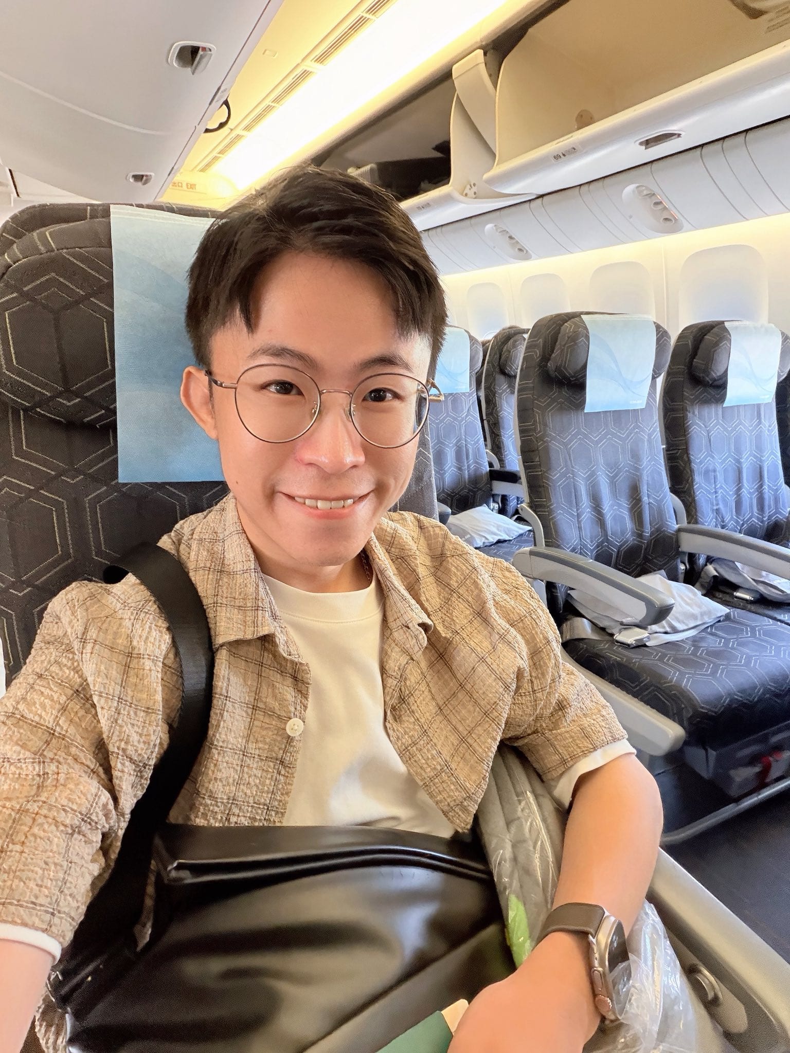 我戴眼鏡、背著包包在飛機座位上自拍