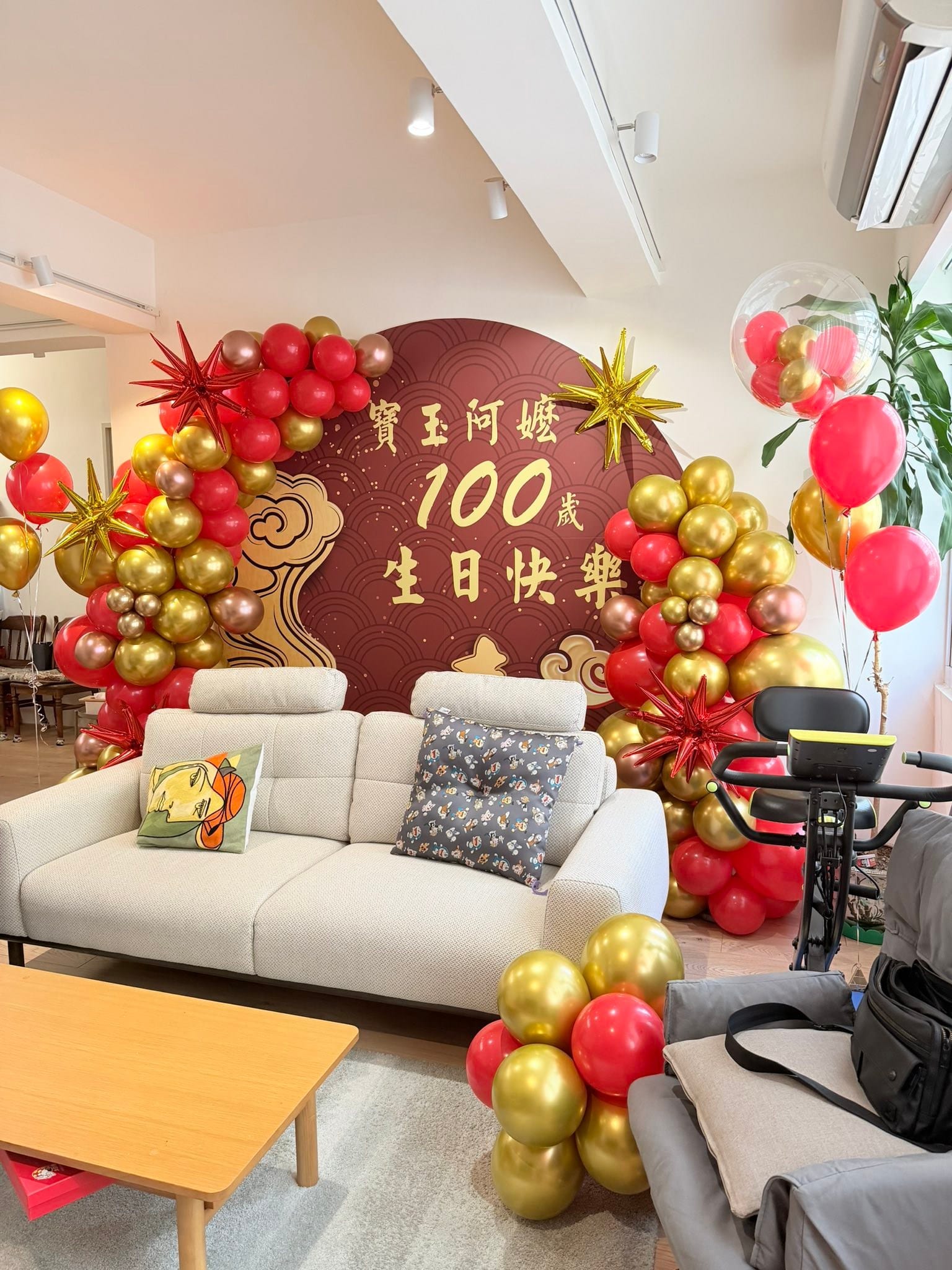 直式全景照，客廳裡的紅金氣球拱、透明泡泡球與地面金色氣球堆