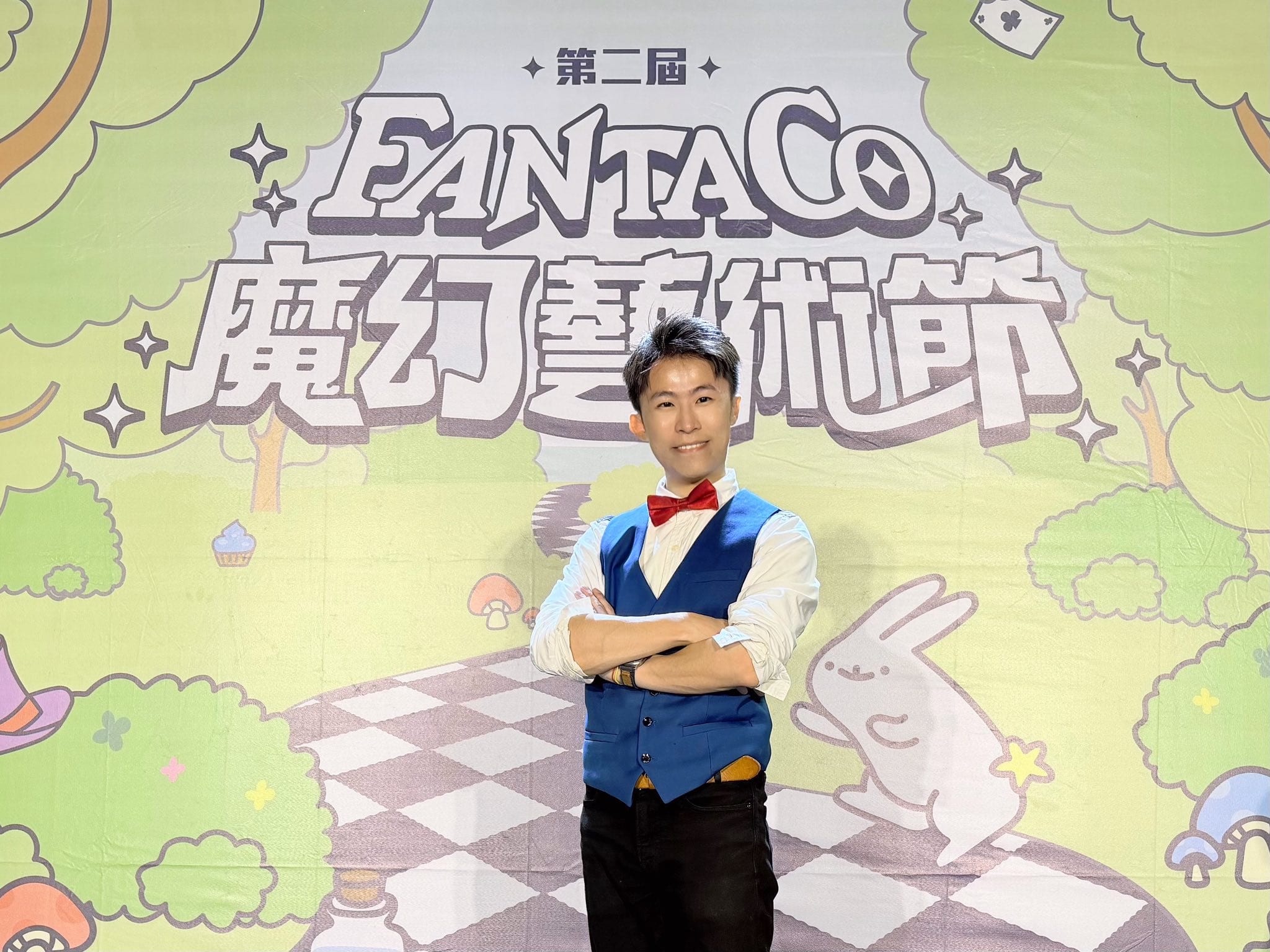 柯男雙手抱胸站在第二屆 FANTACO 魔幻藝術節主視覺背板前