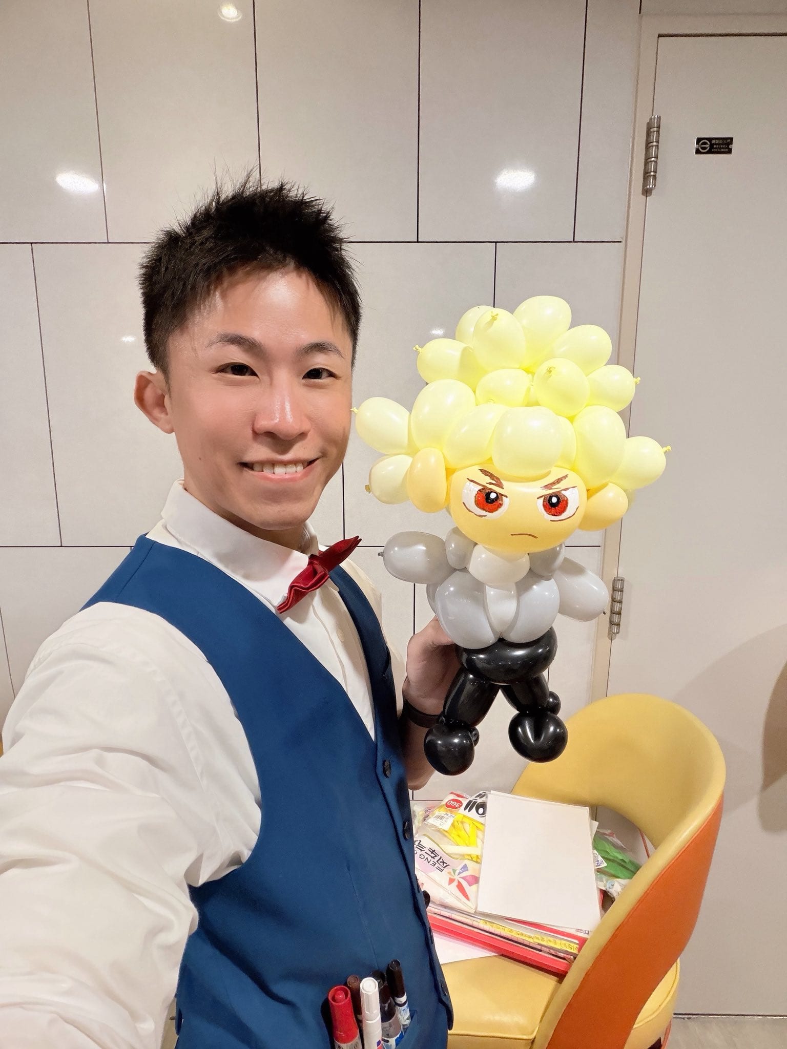 12 月抓周：柯男手拿爆豪造型氣球自拍，黃色刺刺頭髮、灰色制服