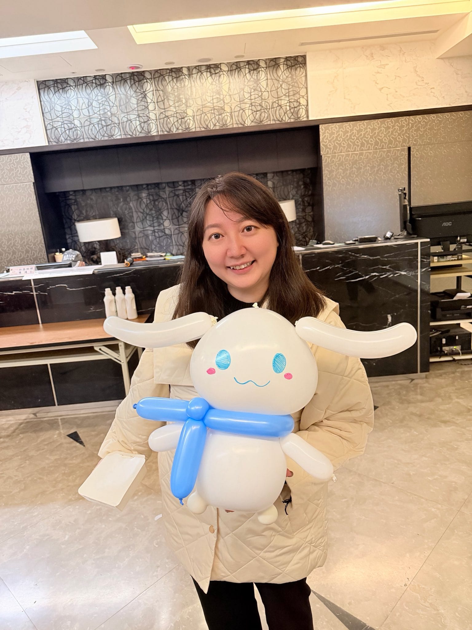 女生抱著白色大耳朵、藍色眼睛、藍色圍巾的大耳狗造型氣球