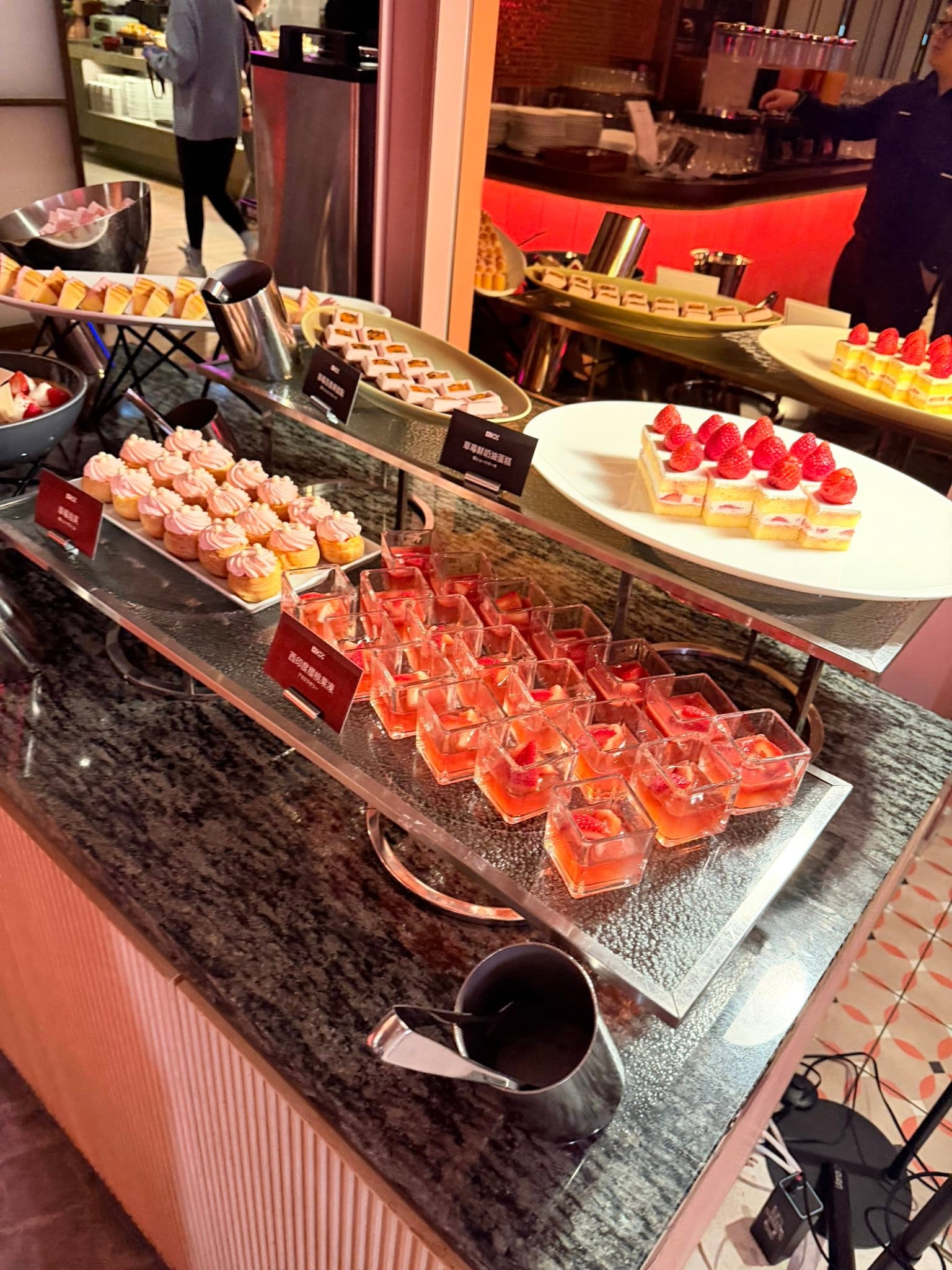 自助餐甜點區的草莓蛋糕、粉色馬卡龍與紅色果凍杯
