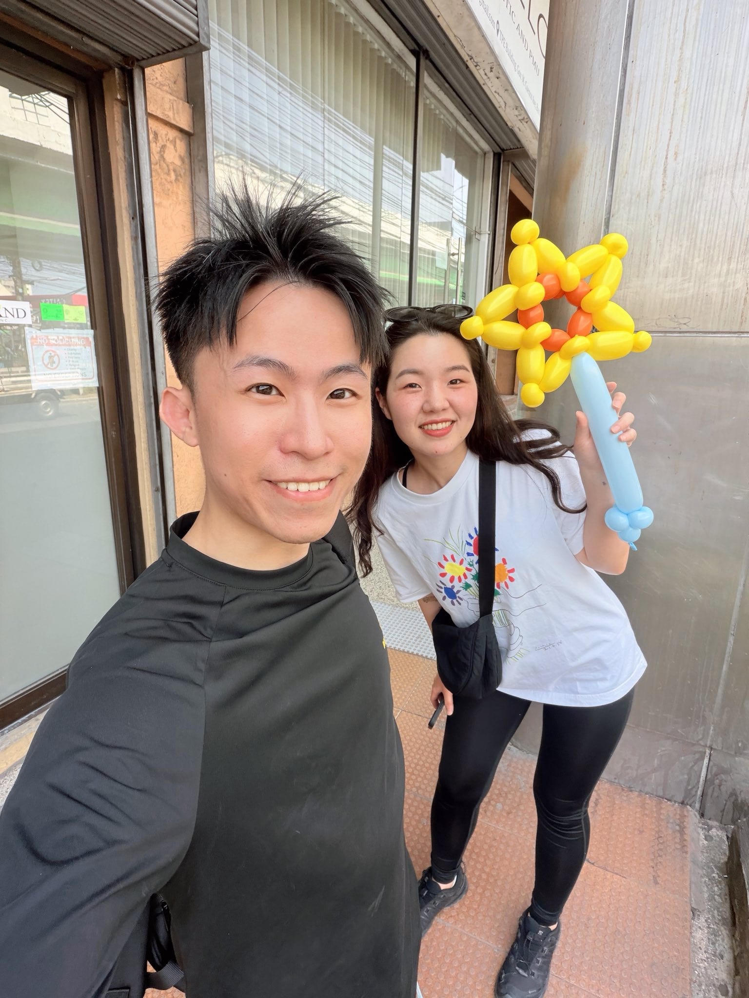 同學拿著黃色向日葵造型氣球手拿棒和我合照