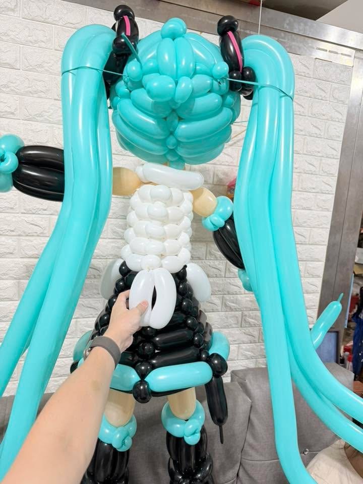 初音未來氣球人偶背面特寫,藍綠色長氣球編成的頭髮與垂到腳邊的雙馬尾