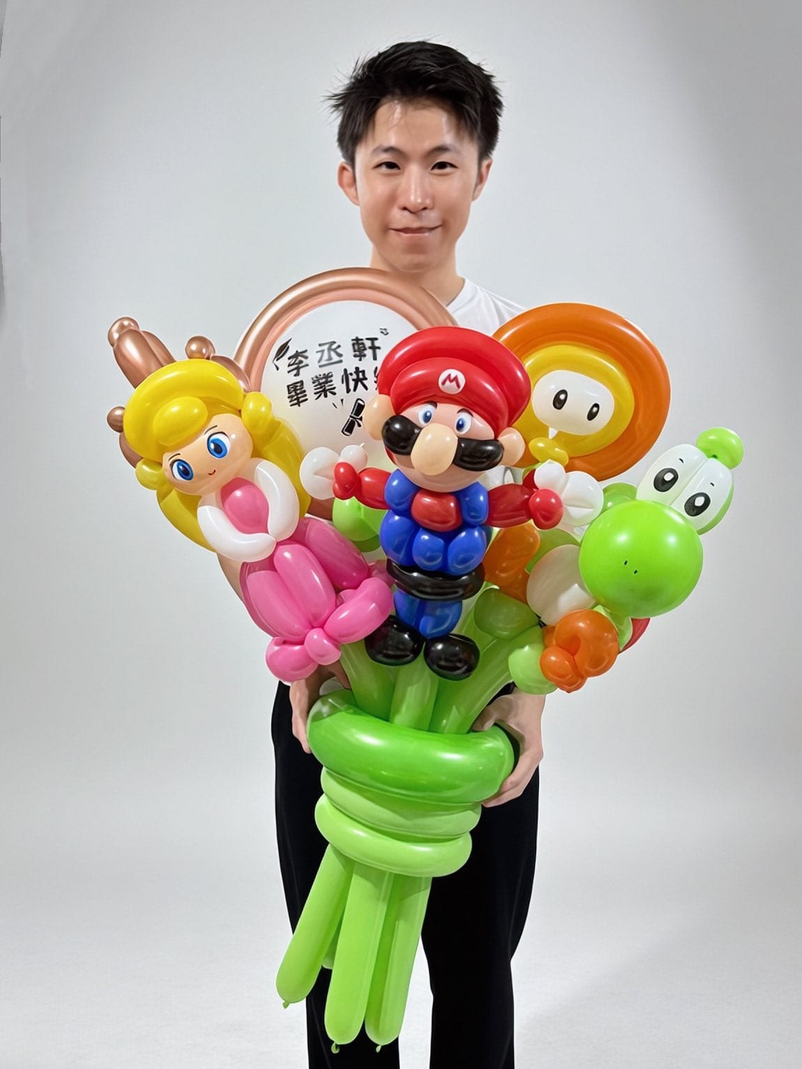 柯男雙手捧著瑪利歐畢業氣球花束,花束下方以綠色長條氣球纏繞成握把