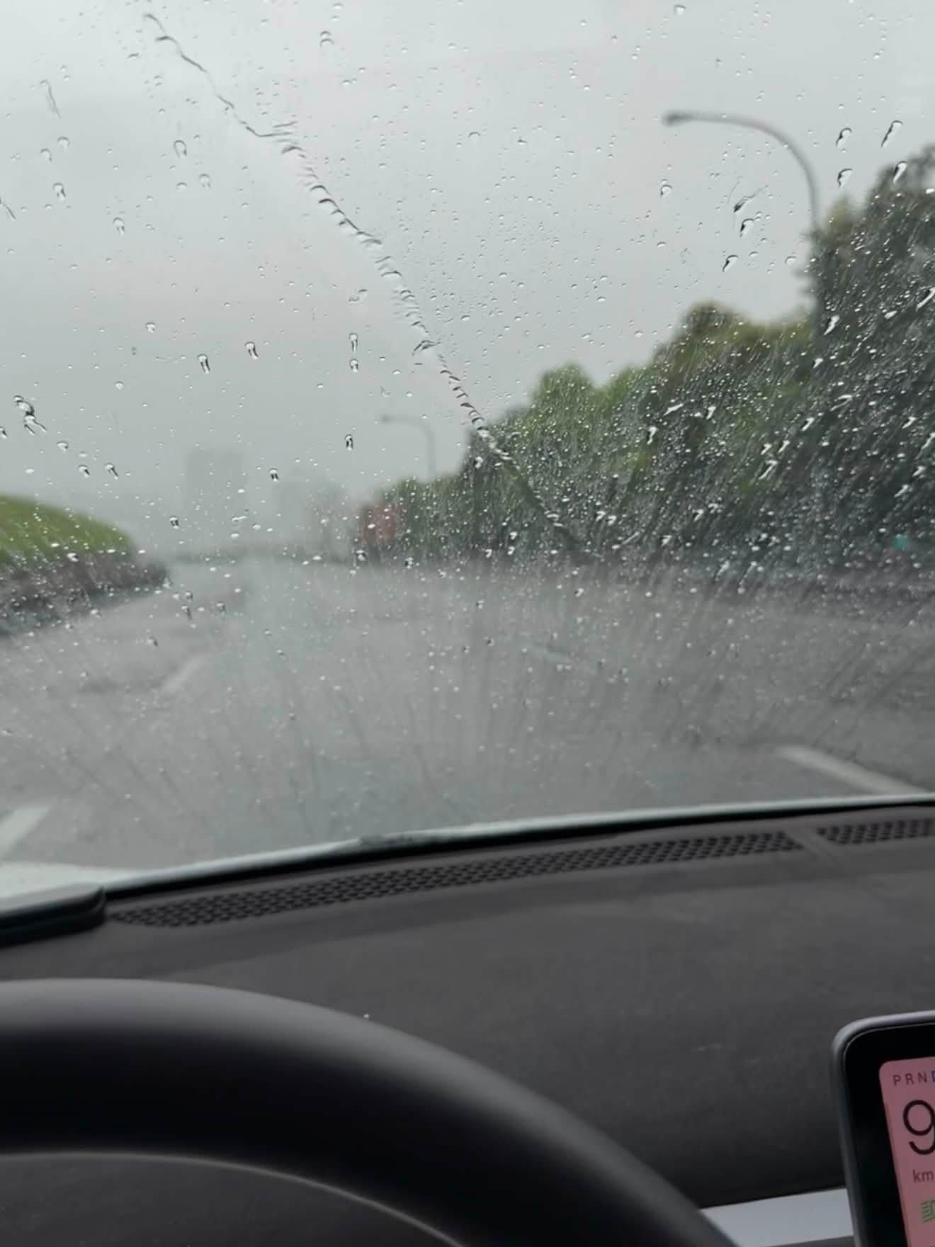 颱風天早晨從車內看出去的快速道路，擋風玻璃布滿雨滴，路上幾乎沒有車