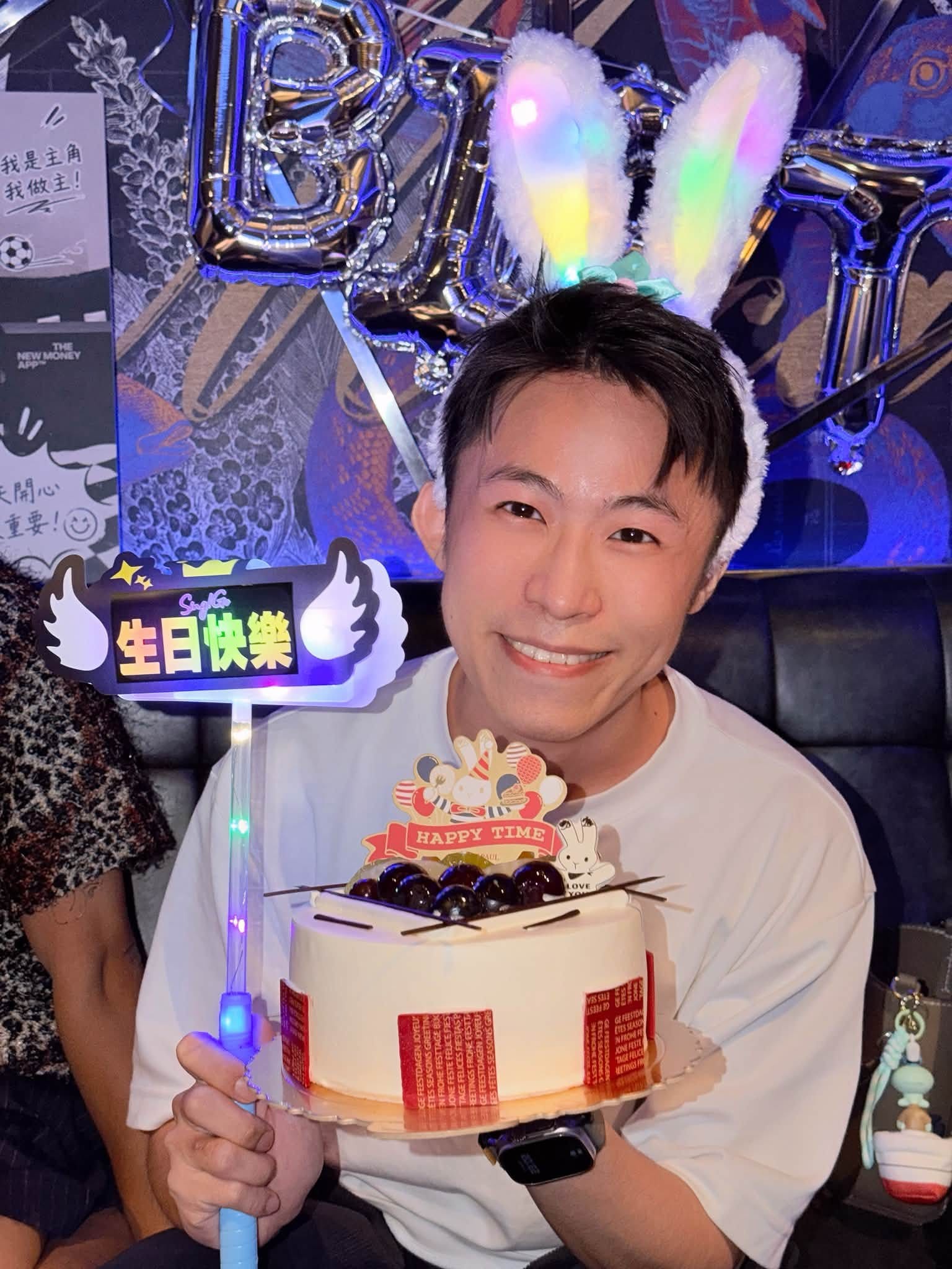 我戴著發光兔耳髮箍，捧著生日蛋糕和生日快樂手牌