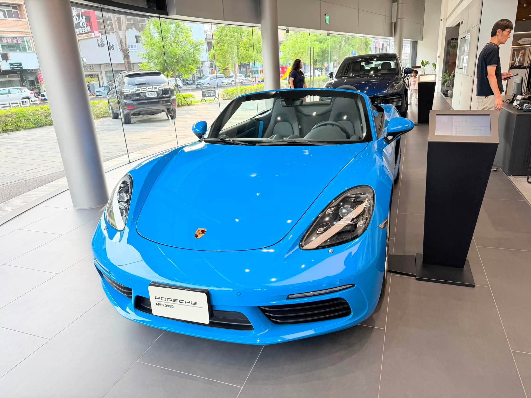 保時捷展示中心內一台天藍色敞篷跑車,車頭掛著 PORSCHE APPROVED 牌