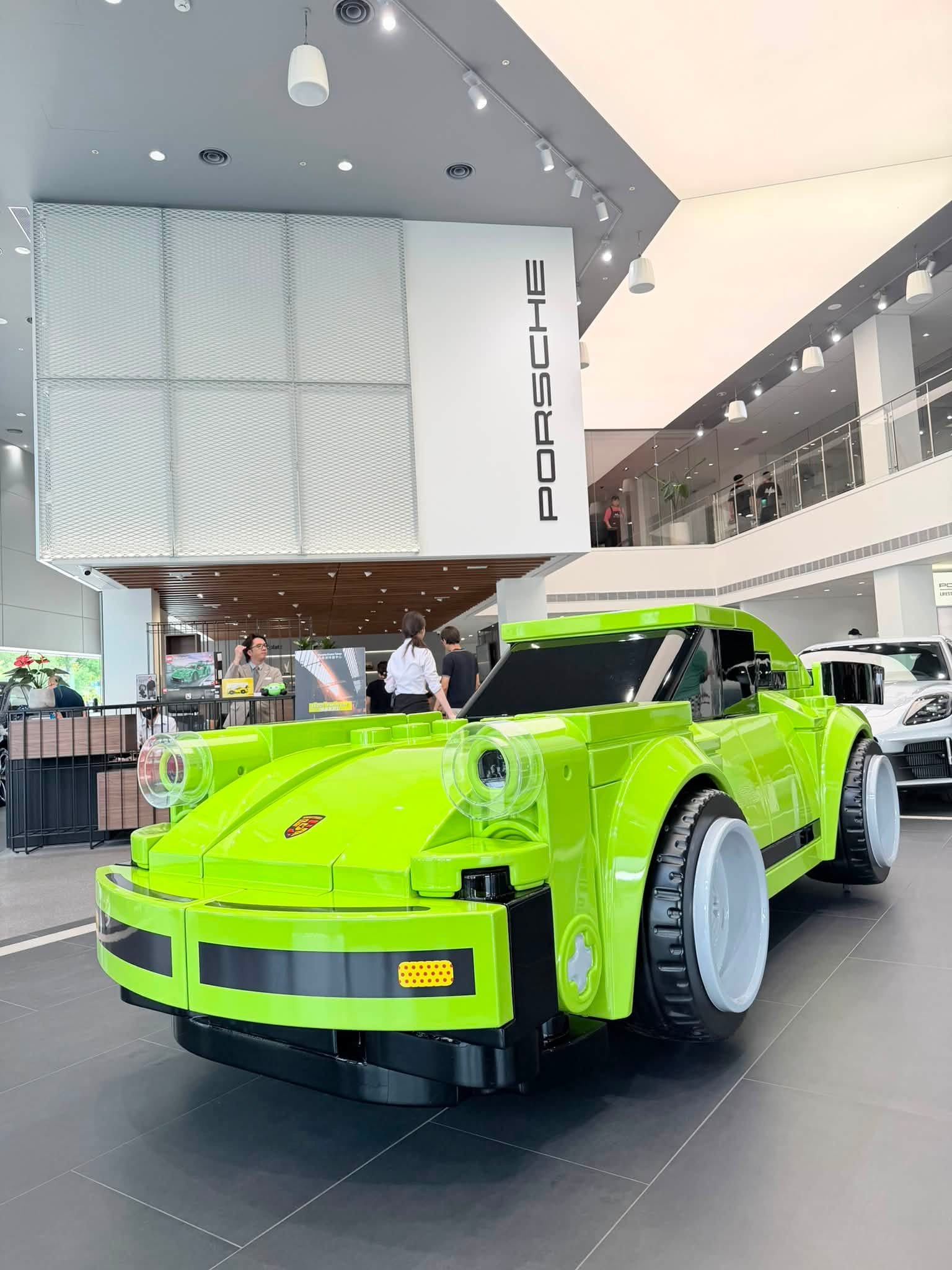 螢光綠色大型樂高保時捷停在展間中央,後方牆面有 PORSCHE 字樣與挑高二樓