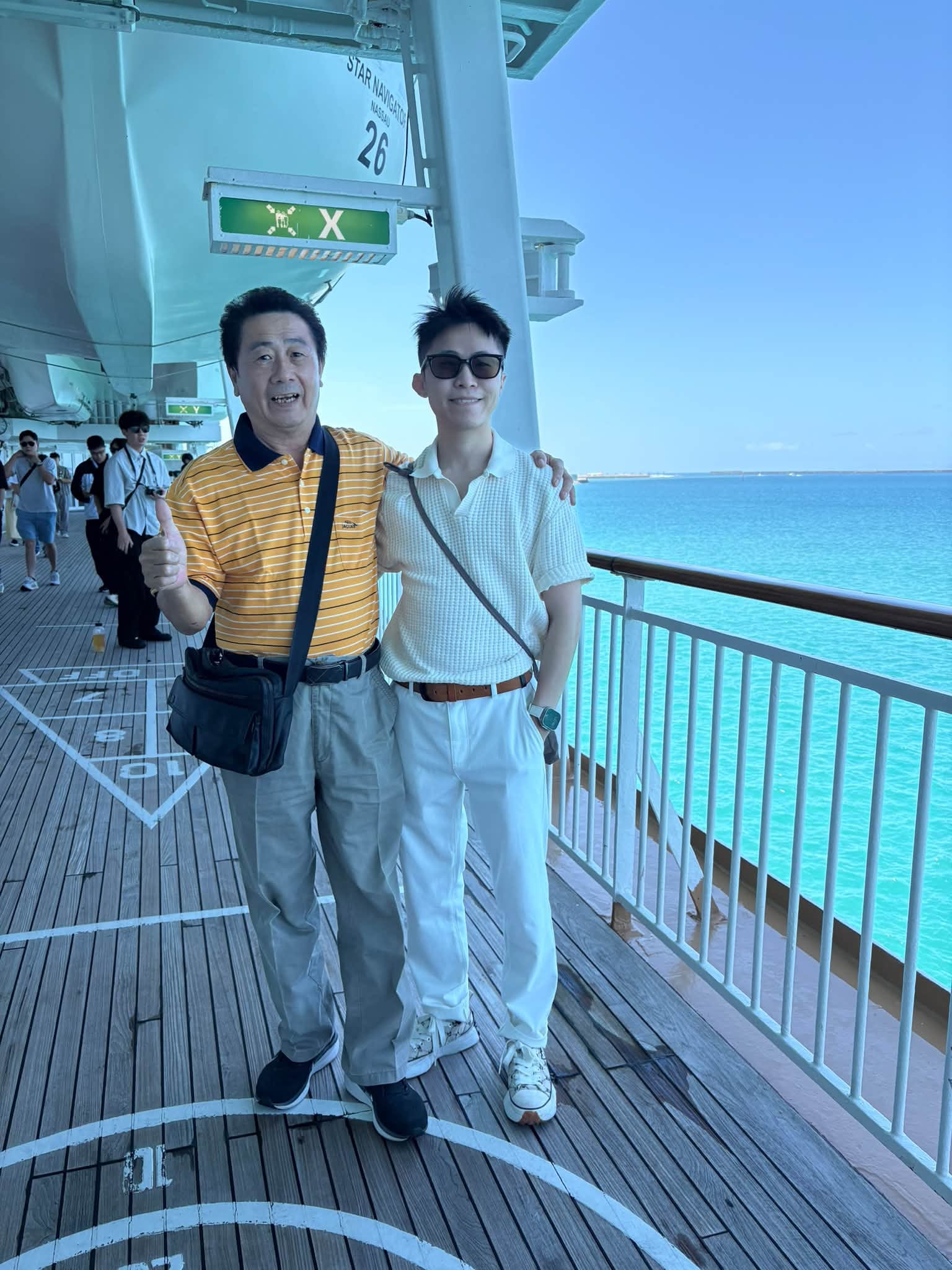 我和爸爸穿著條紋衫在郵輪甲板欄杆旁合照