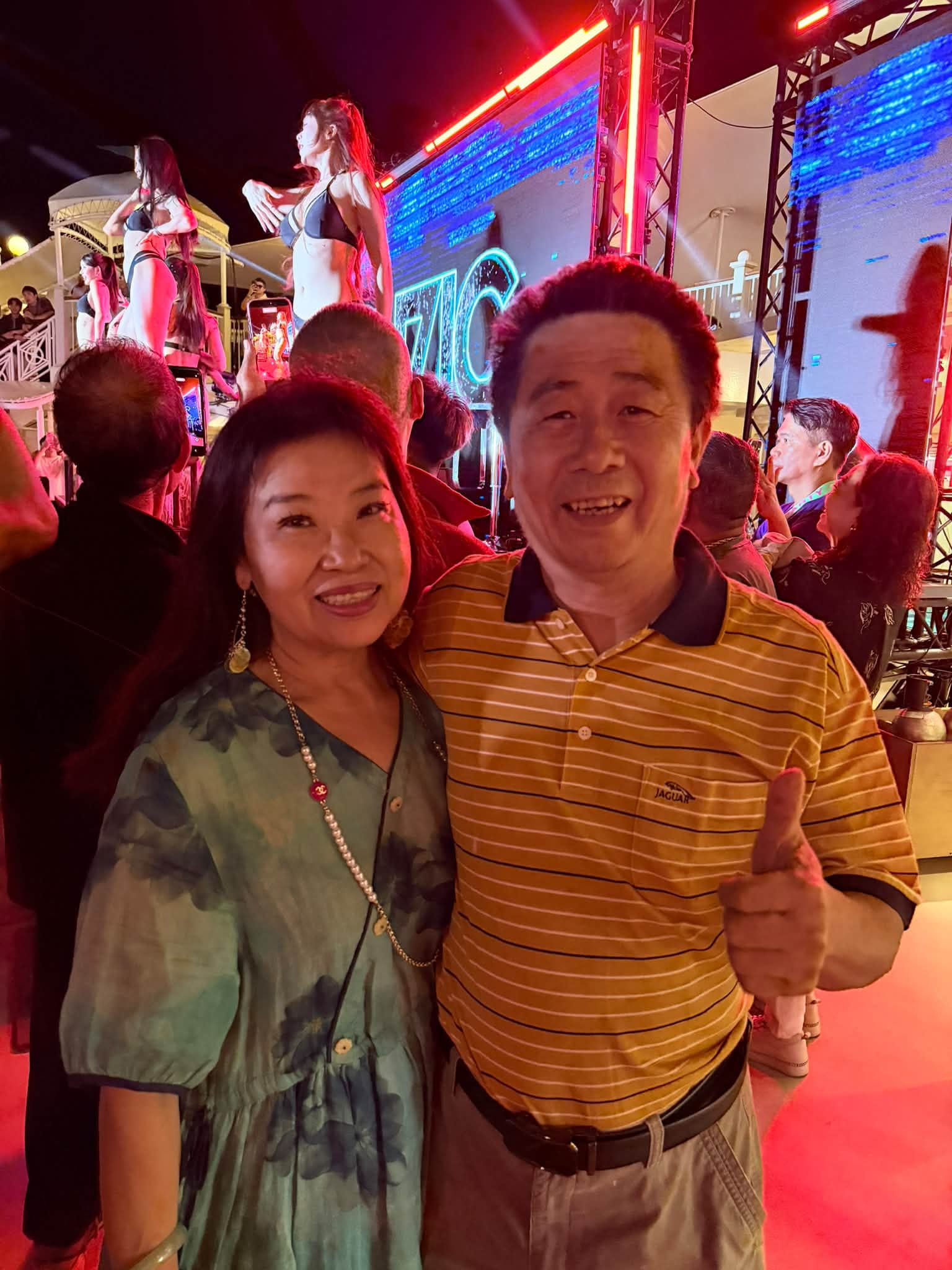 爸媽在郵輪主舞台的電音派對前比讚合影