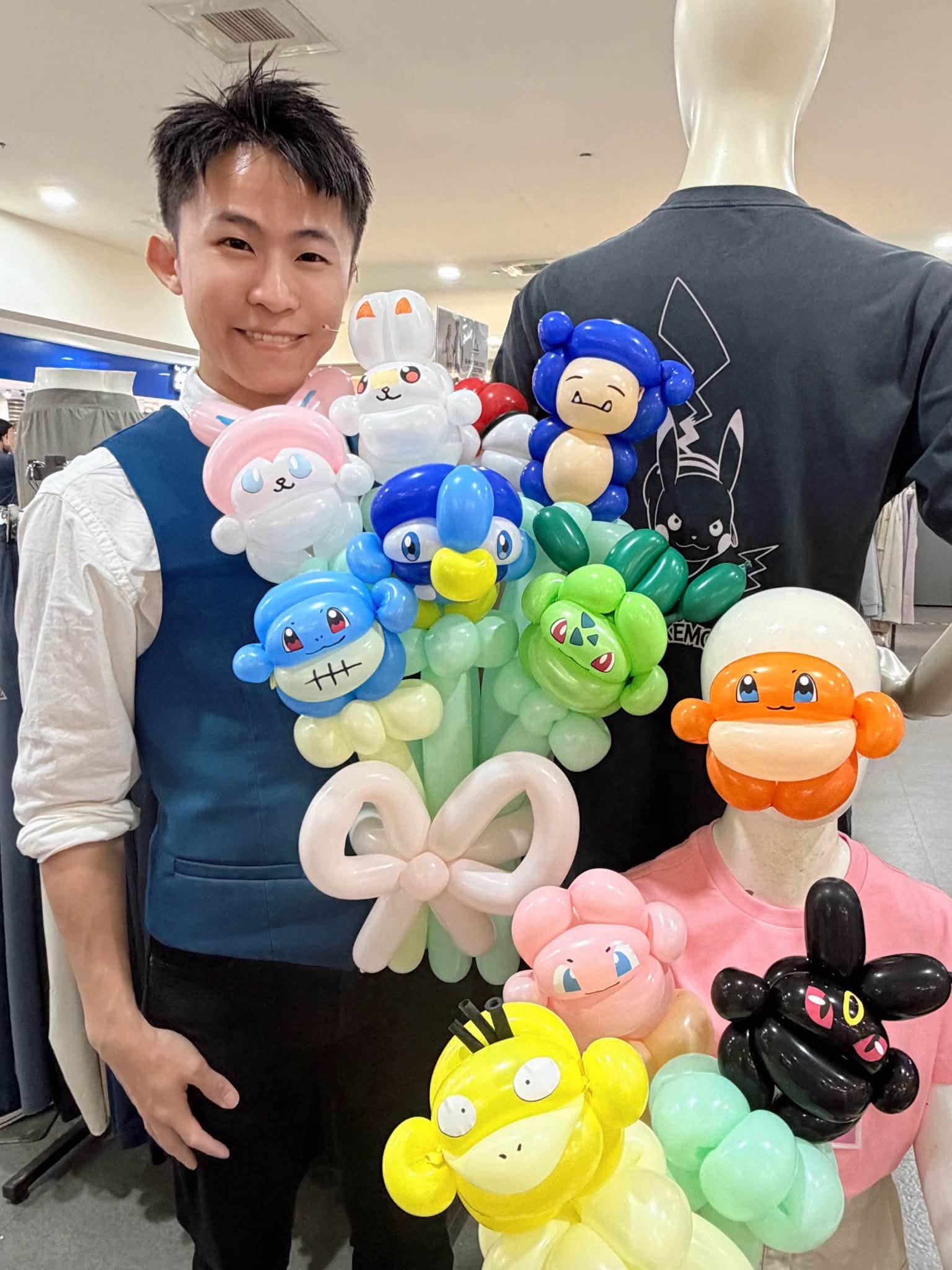 柯男在桃園萬家福佐丹奴店內抱著一大把造型氣球，有黃色可達鴨、綠色妙蛙種子與藍、粉色角色氣球