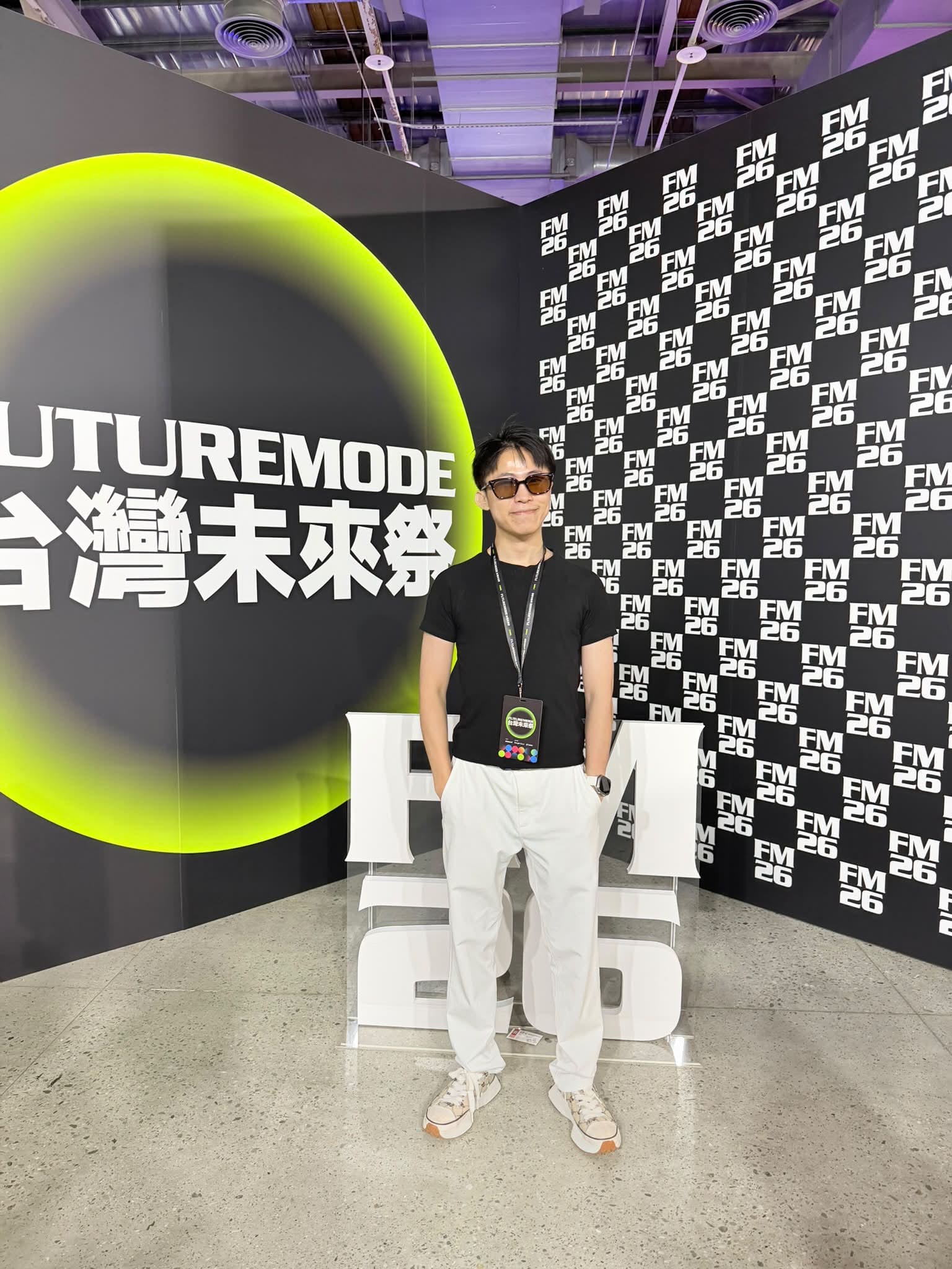 我戴墨鏡、穿黑色 T 恤，站在台灣未來祭的背板前